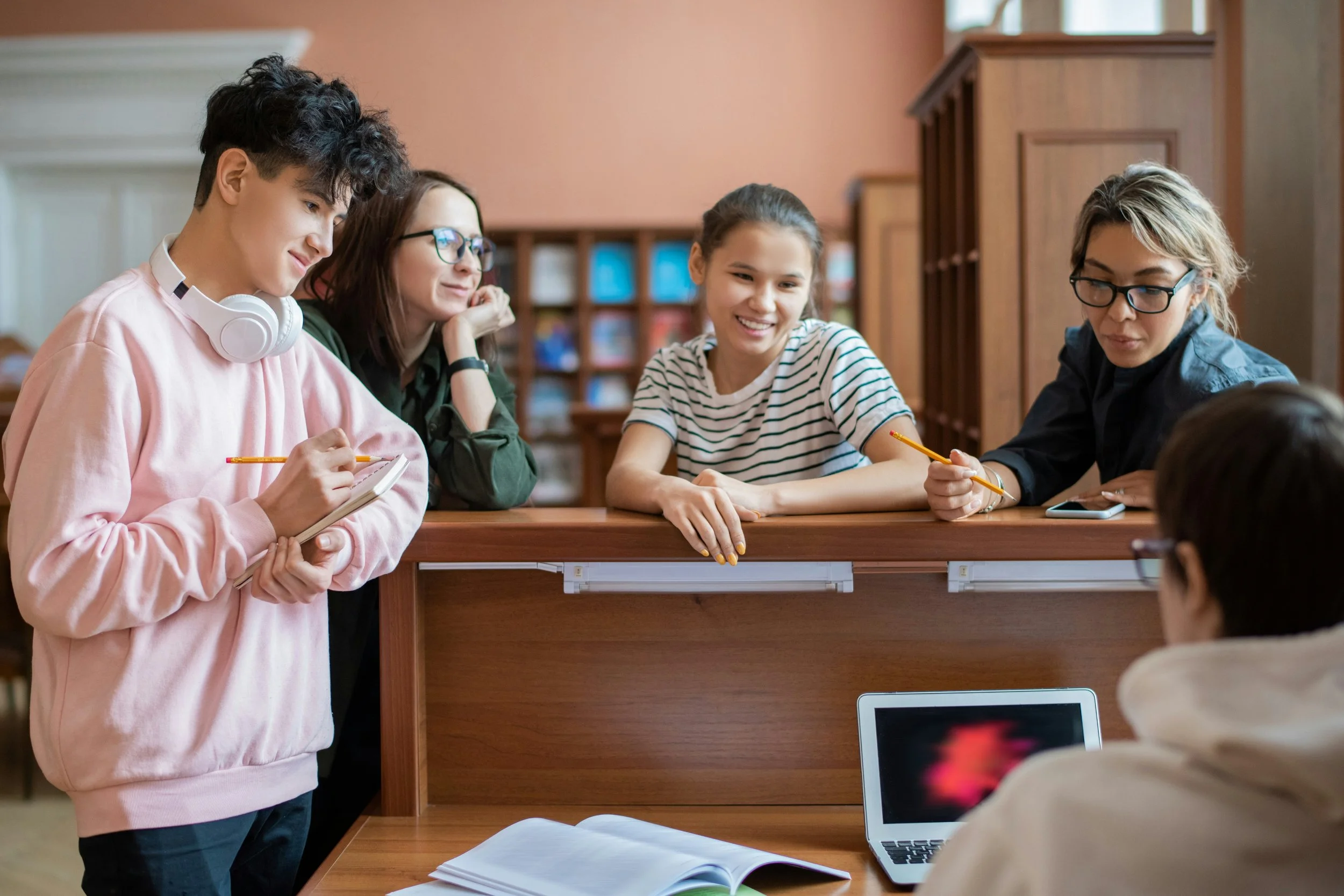 A small group of high school students and their teacher in a discussion.