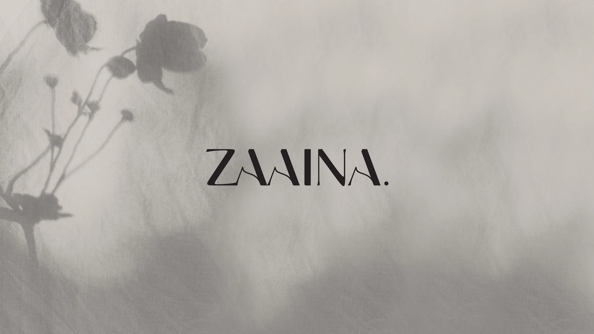 Black text 'ZAINA.' on a light background with a shadow of a flower in the upper left corner.