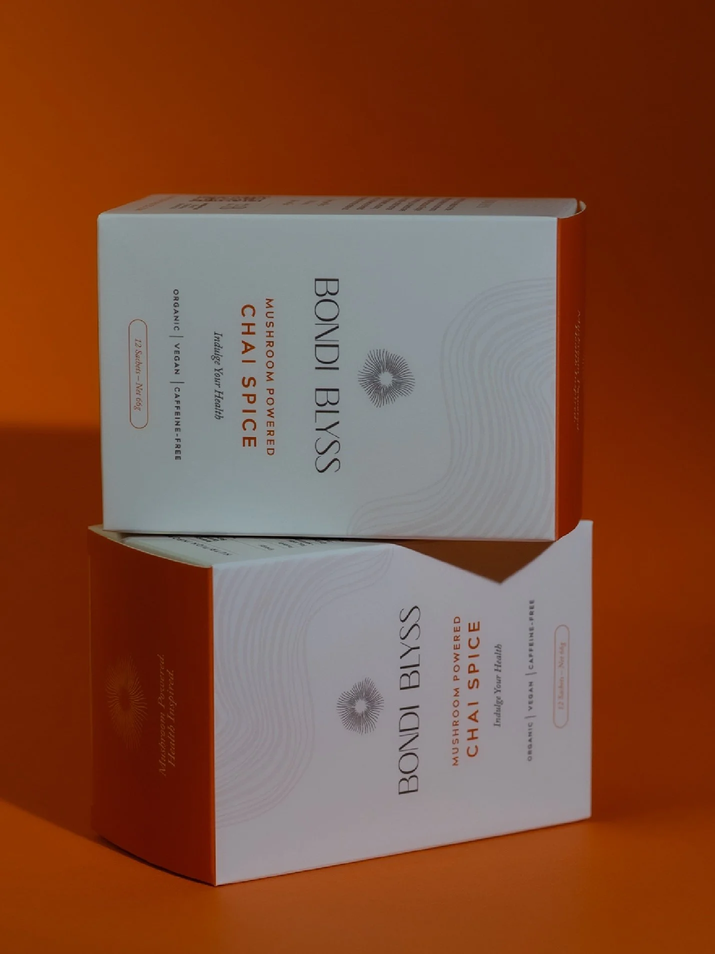 A white box of Bondi Bliss mushroom-powered chai spice tea placed on an orange background, with the box slightly tilted.