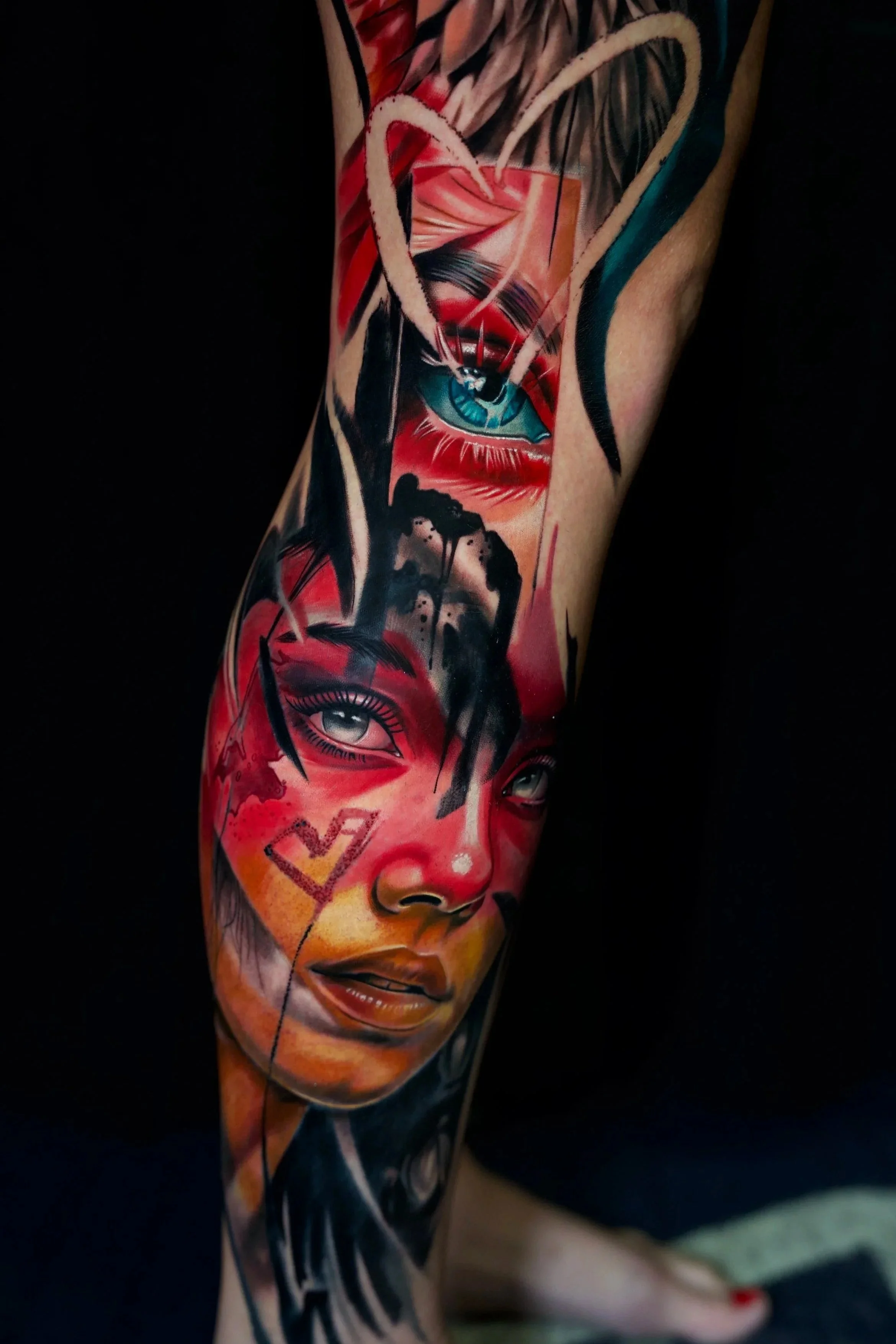 Colorful tattoo sleeve featuring realistic portraits of a woman's face with makeup, hearts, and abstract elements.