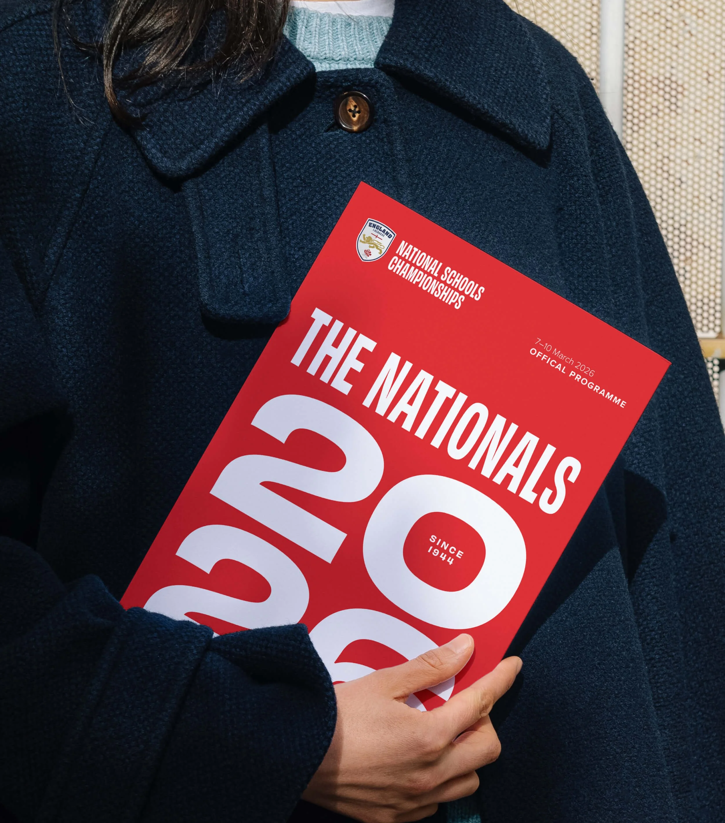 A woman holding the the Nationals official programme.