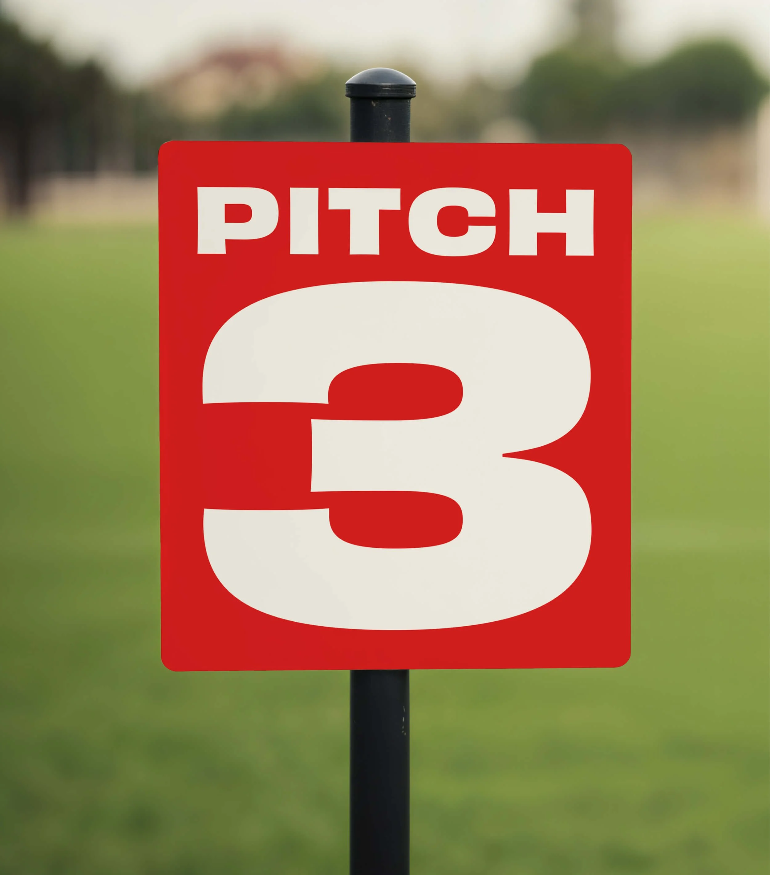A red sign displaying a large number 3 with a field in the background.