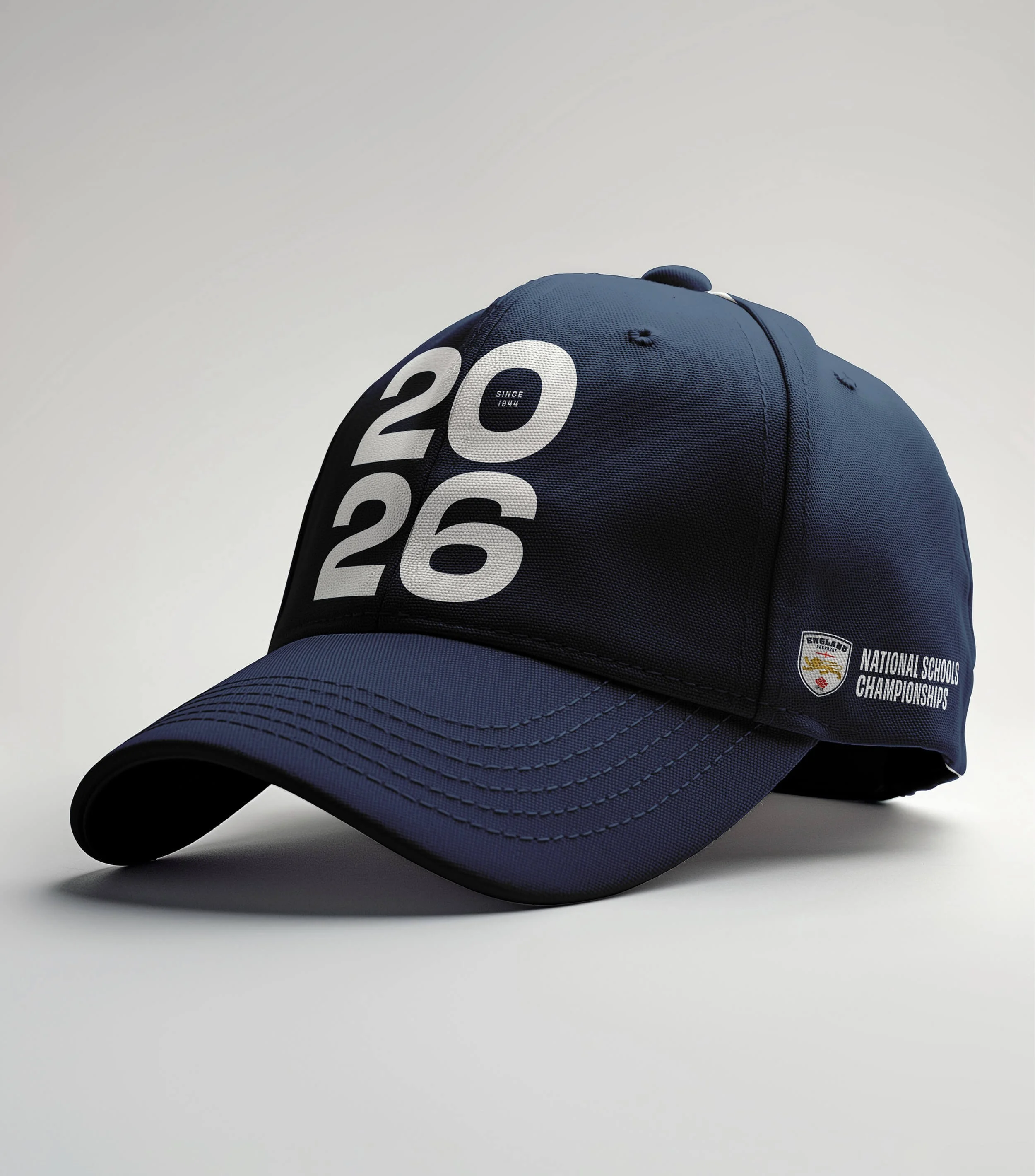 A dark blue cap on a grey surface showing the England Lacrosse National Schools Championships logo.