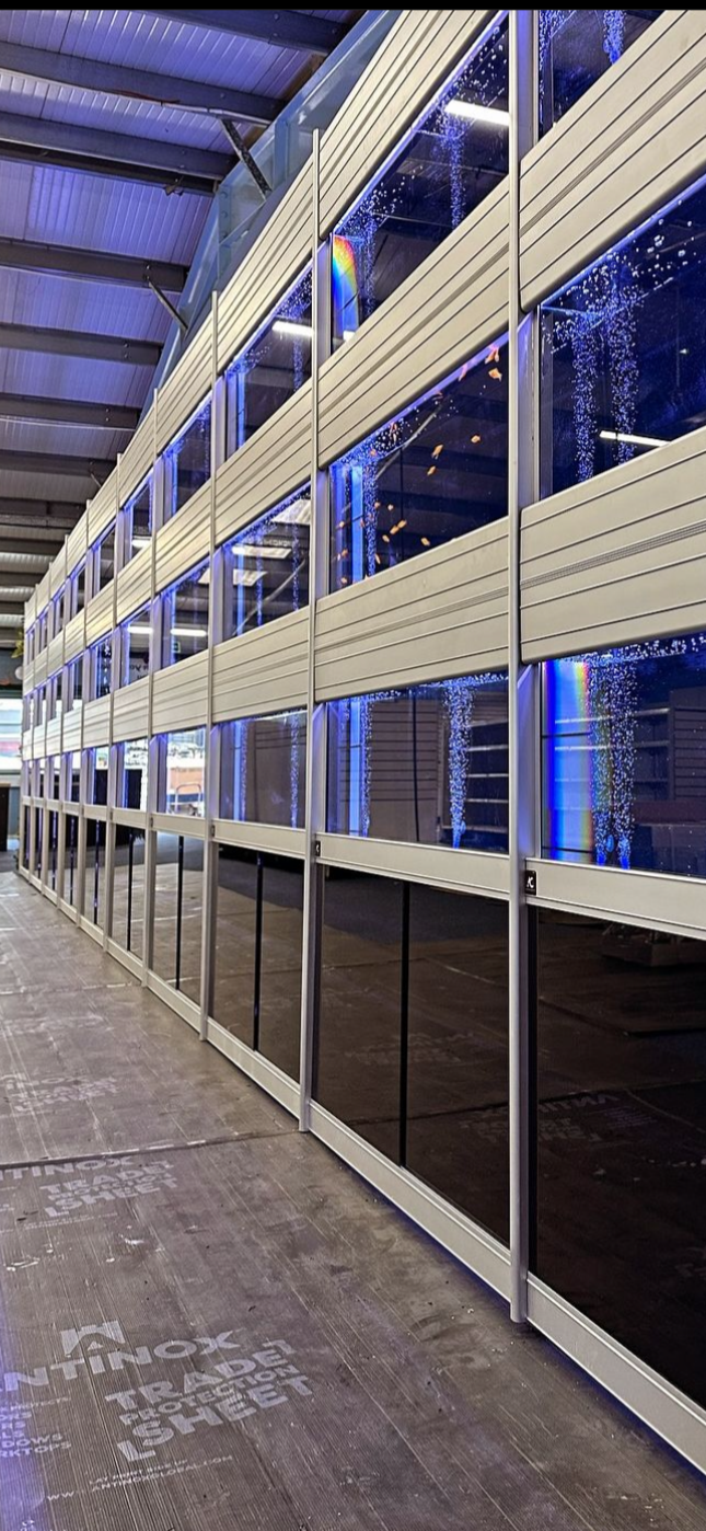 Storefront with large glass windows and siding, inside a warehouse with visible ceiling beams and a concrete floor.