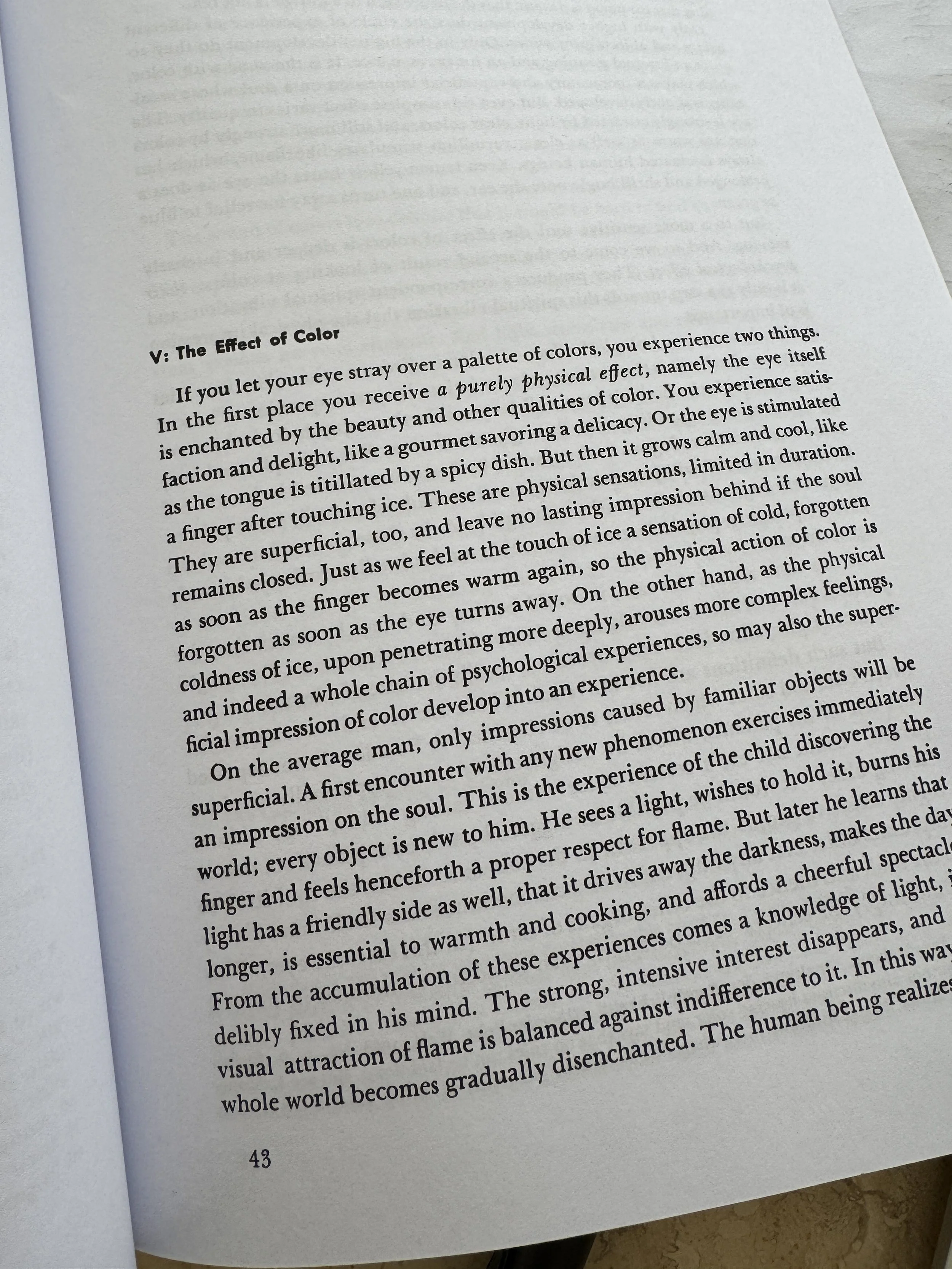 Aufgeschlagenes Buch von Wassily Kandinsky auf einem Schreibtisch. Die Seiten zeigen kunsttheoretische Texte über das Geistige in der Kunst, während die Arbeitsumgebung auf intensive Recherche und Reflexion über Farbe und Wahrnehmung verweist.