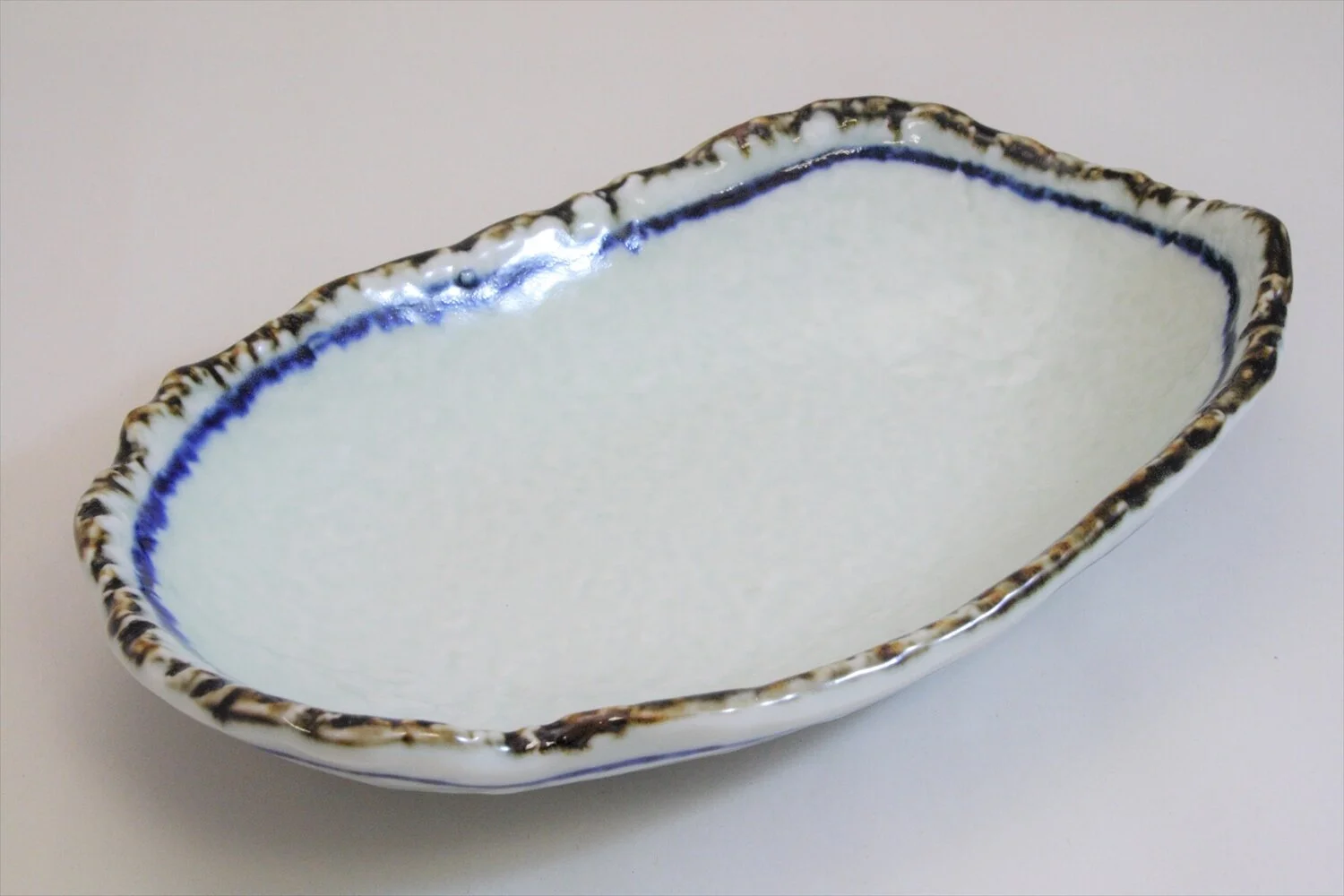 228-4553 White mid oval bowl with deformed blue edge