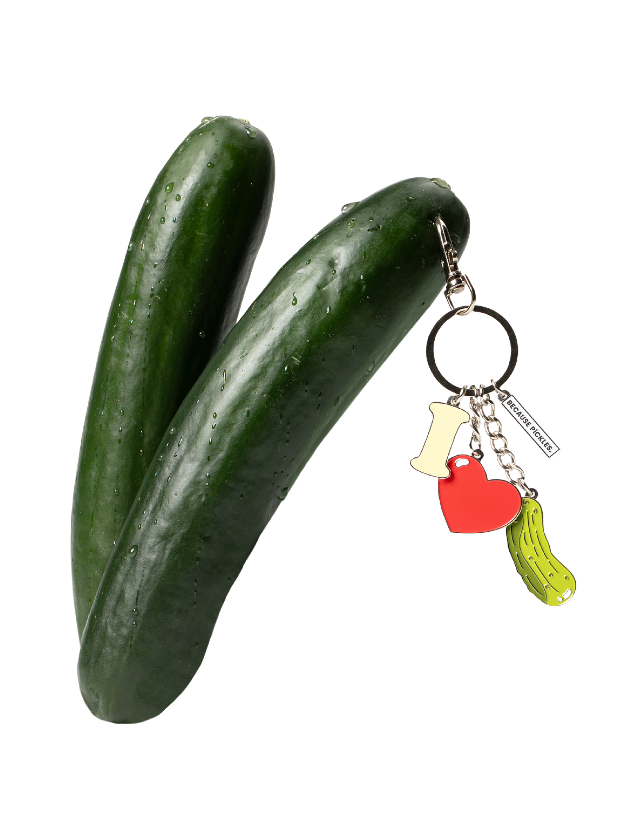 Two cucumbers with water droplets and a keychain attached, featuring a letter 'I', a red heart, and a yellow lime-green cactus-shaped object.