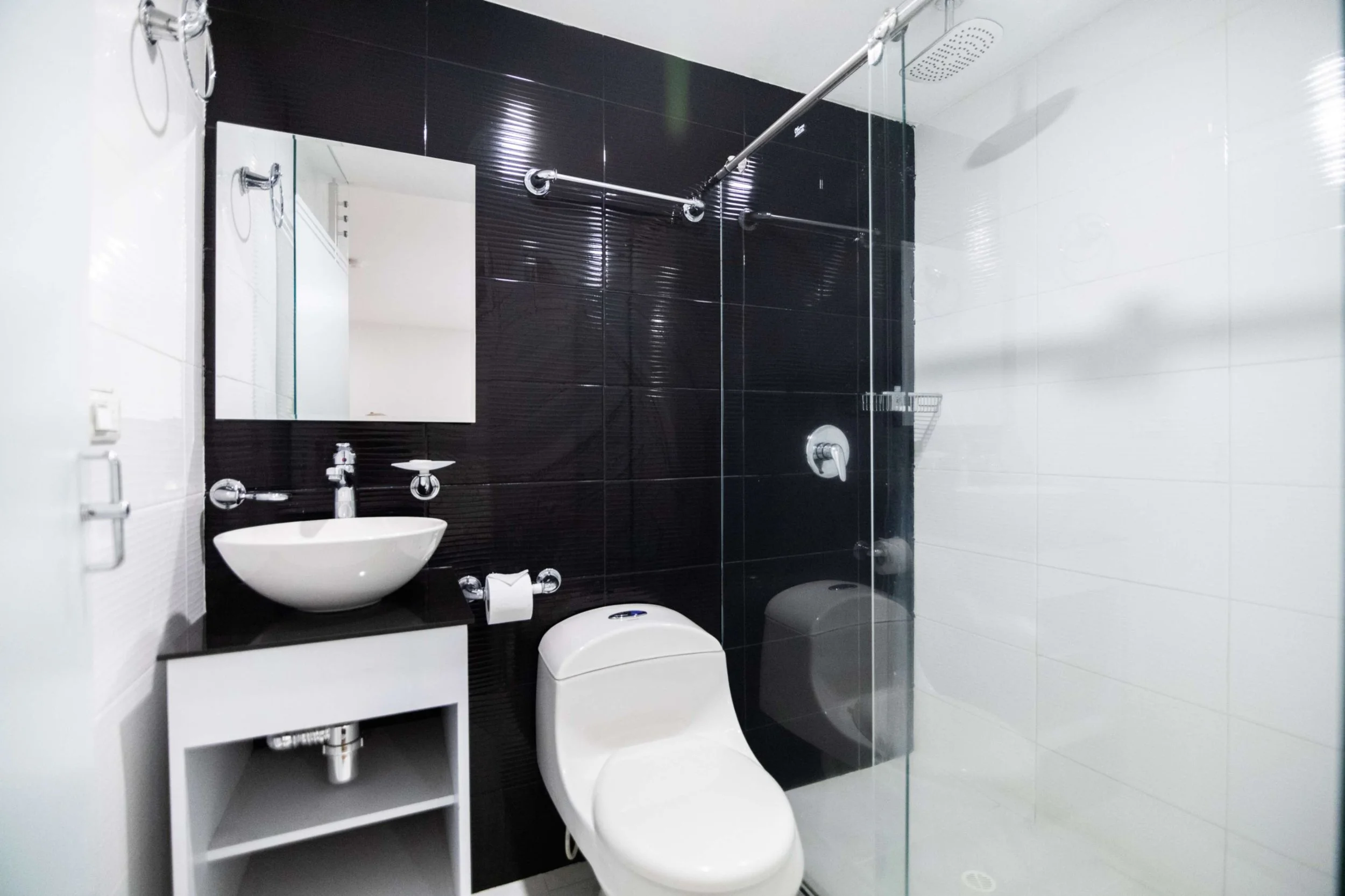 Baño moderno con ducha de vidrio, inodoro y lavabo de cerámica.