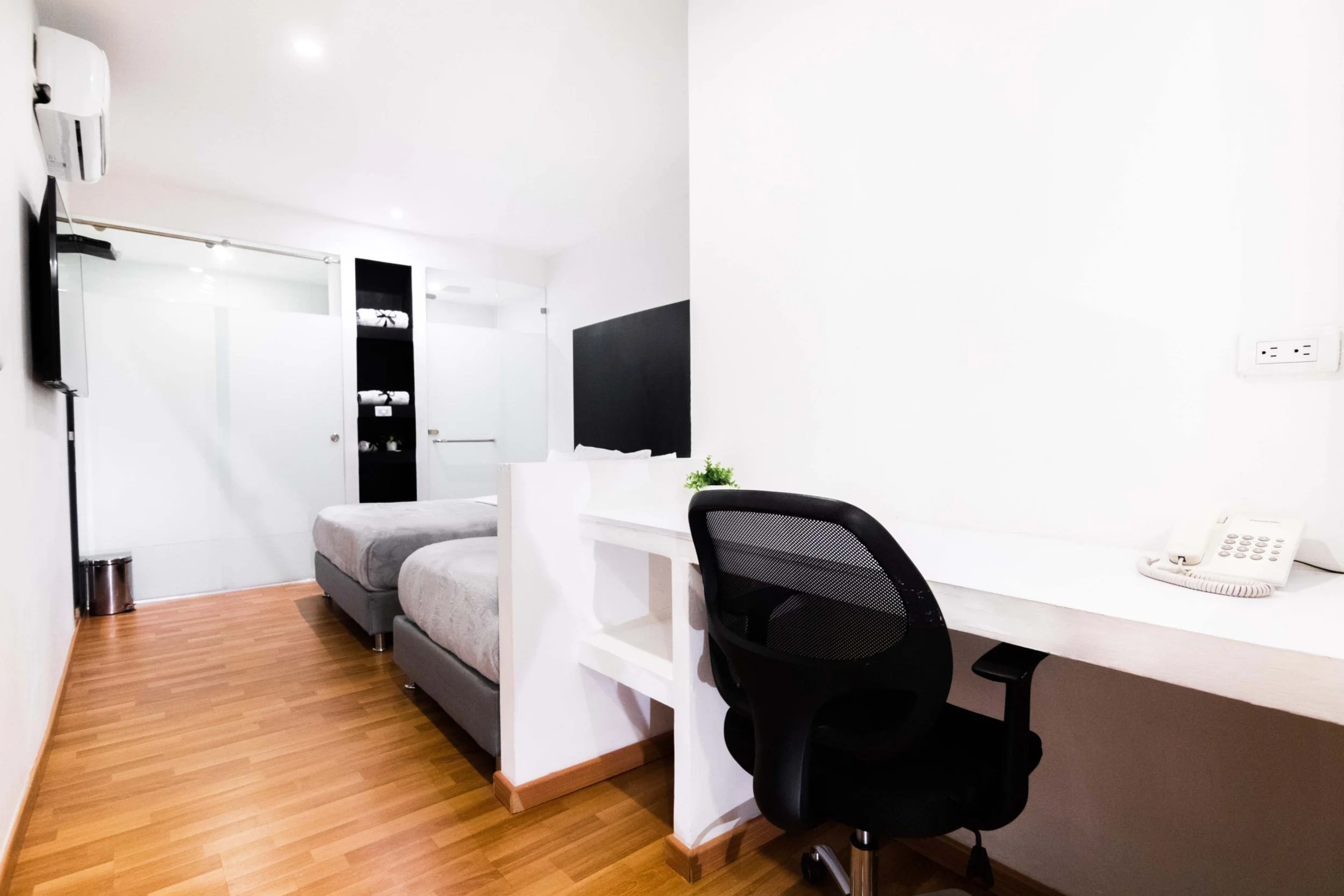 Habitación moderna con dos camas, escritorio con silla y televisor
