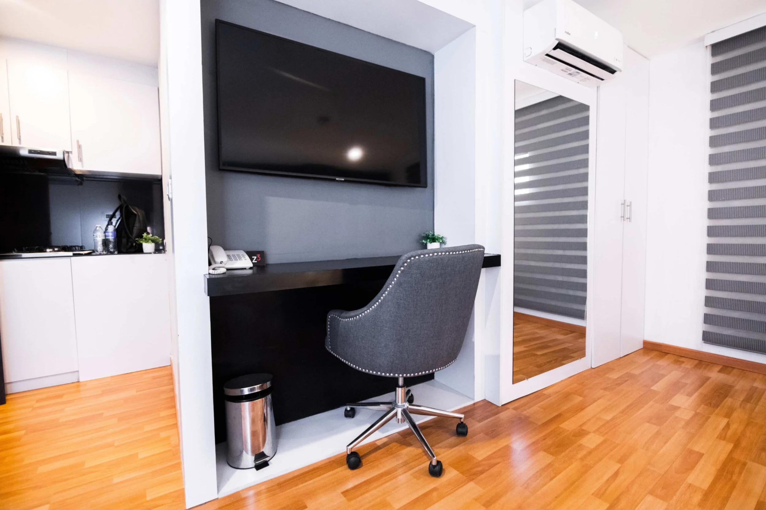 Espacio de trabajo con escritorio, silla de oficina y televisión en la pared