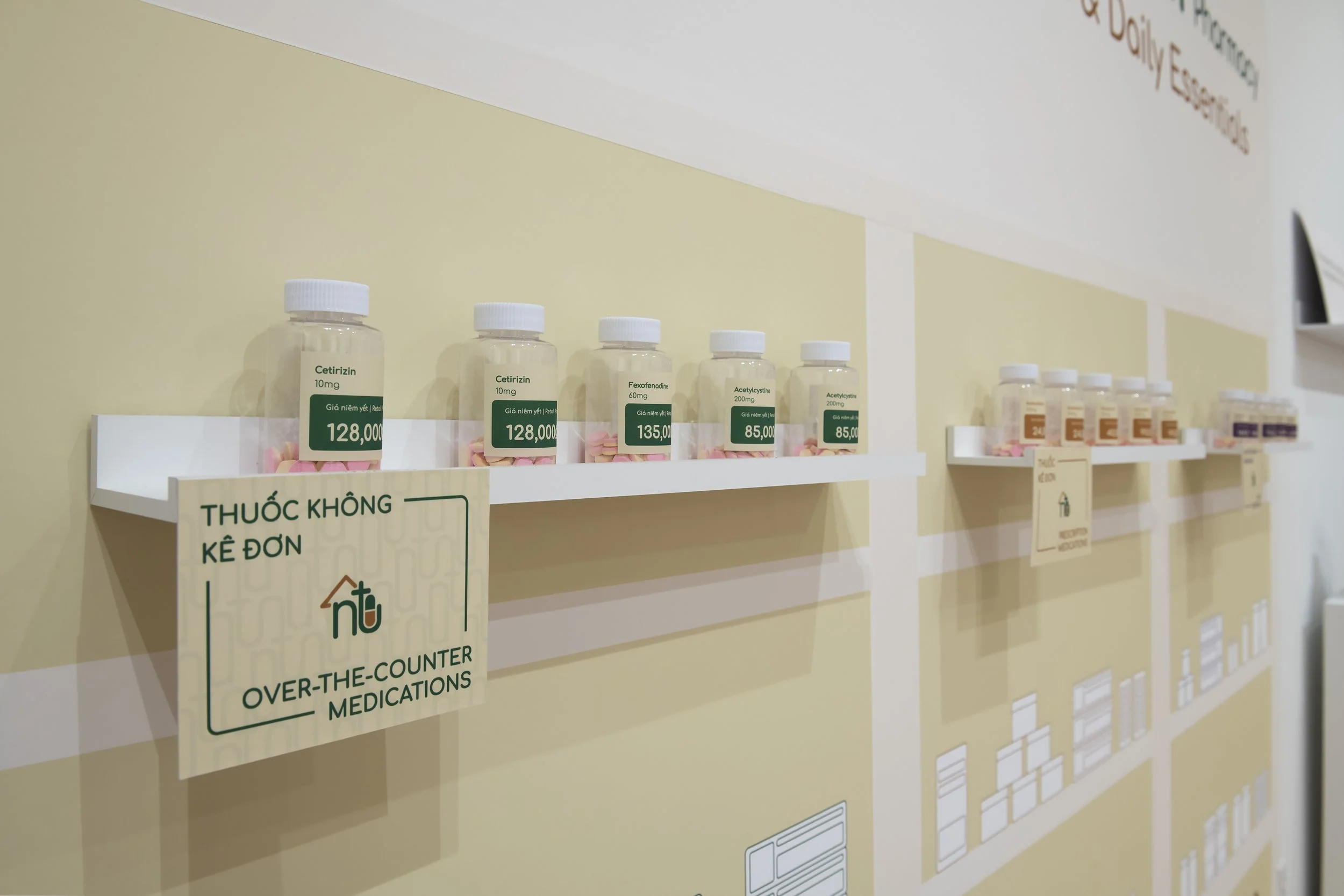 "Ngoc Tram Pharmacy: A Neighborhood Health and Essentials Brand" (detail) 
Bottle labels and category labels on shelves. Inkjet print on adhesive paper, applied to plastic bottles and printed display signage. Dimensions variable. 
Photo credit: John 