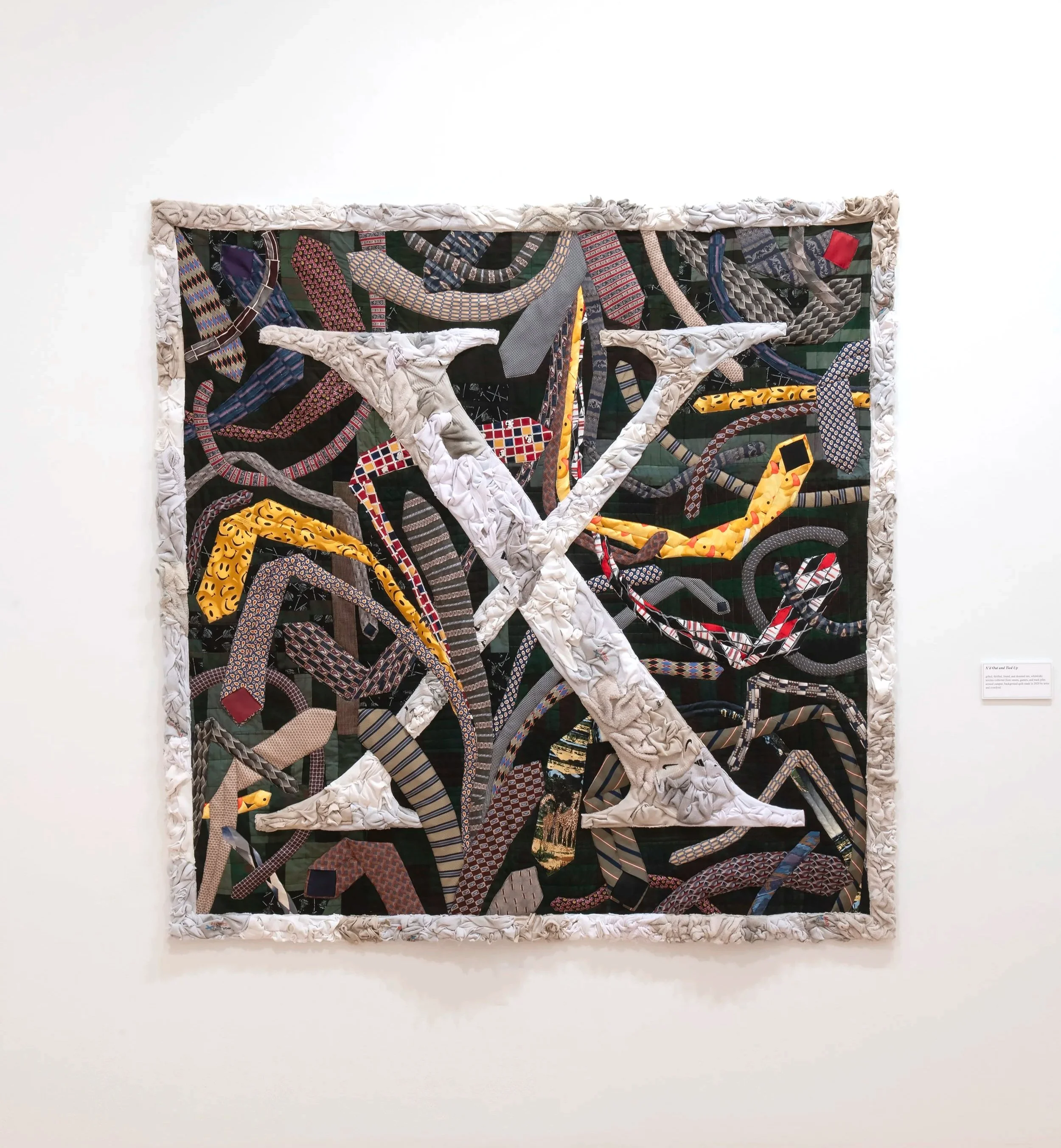 "X’d Out and Tied Up"
gifted, thrifted, found, and donated ties; white(ish) textiles collected from streets, gutters, and 
trash piles around campus; background quilt made in 2020 by artist and overdyed. 65” x 65”. Photo Credit: John Carlano