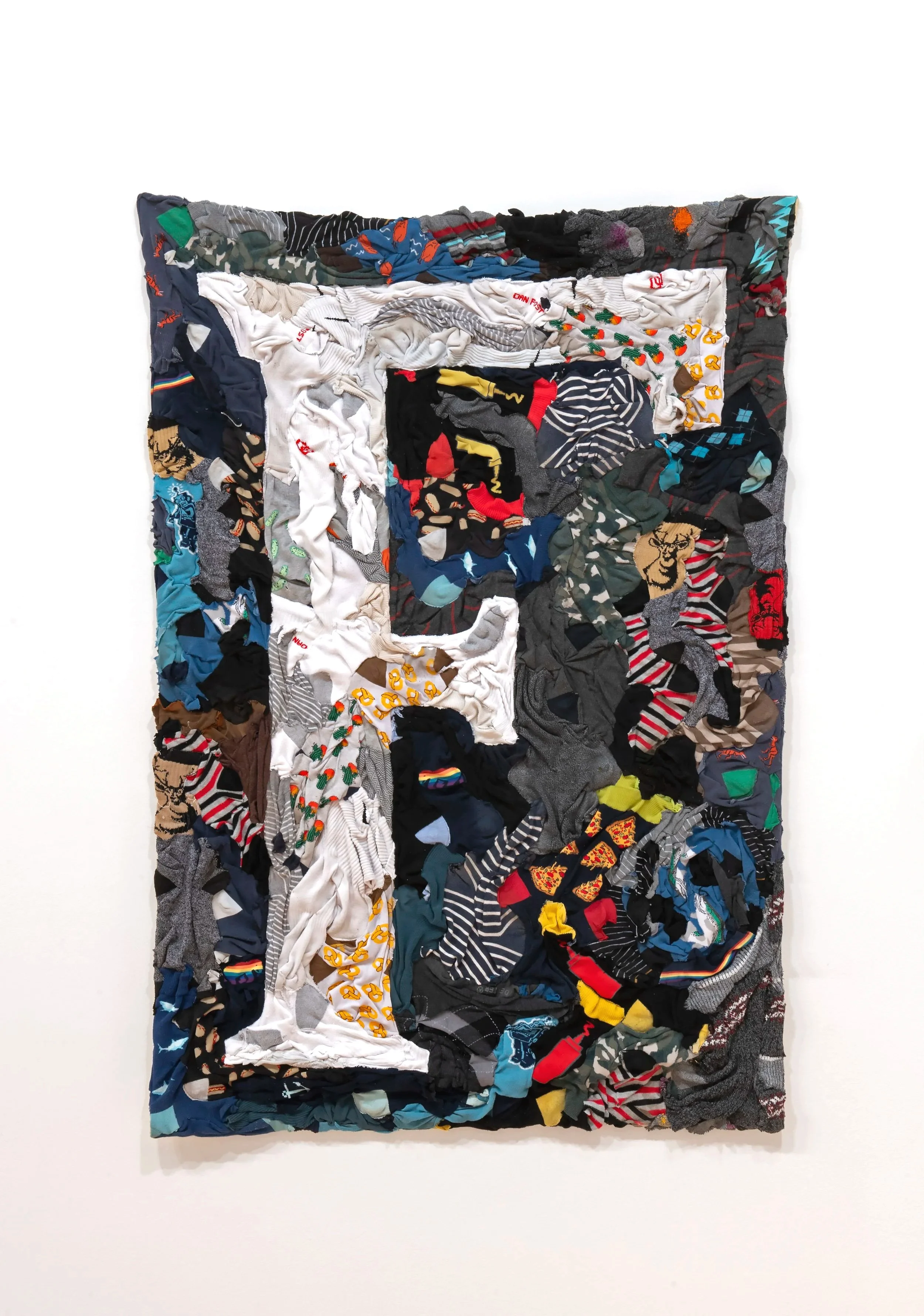 "Diggin’ My Heel into the F Word" 
artists’ worn out/busted out/forgotten/lost crusty socks collected between 2015-2025; backed 
with vintage wool blanket. 37” x 54”. Photo Credit: John Carlano