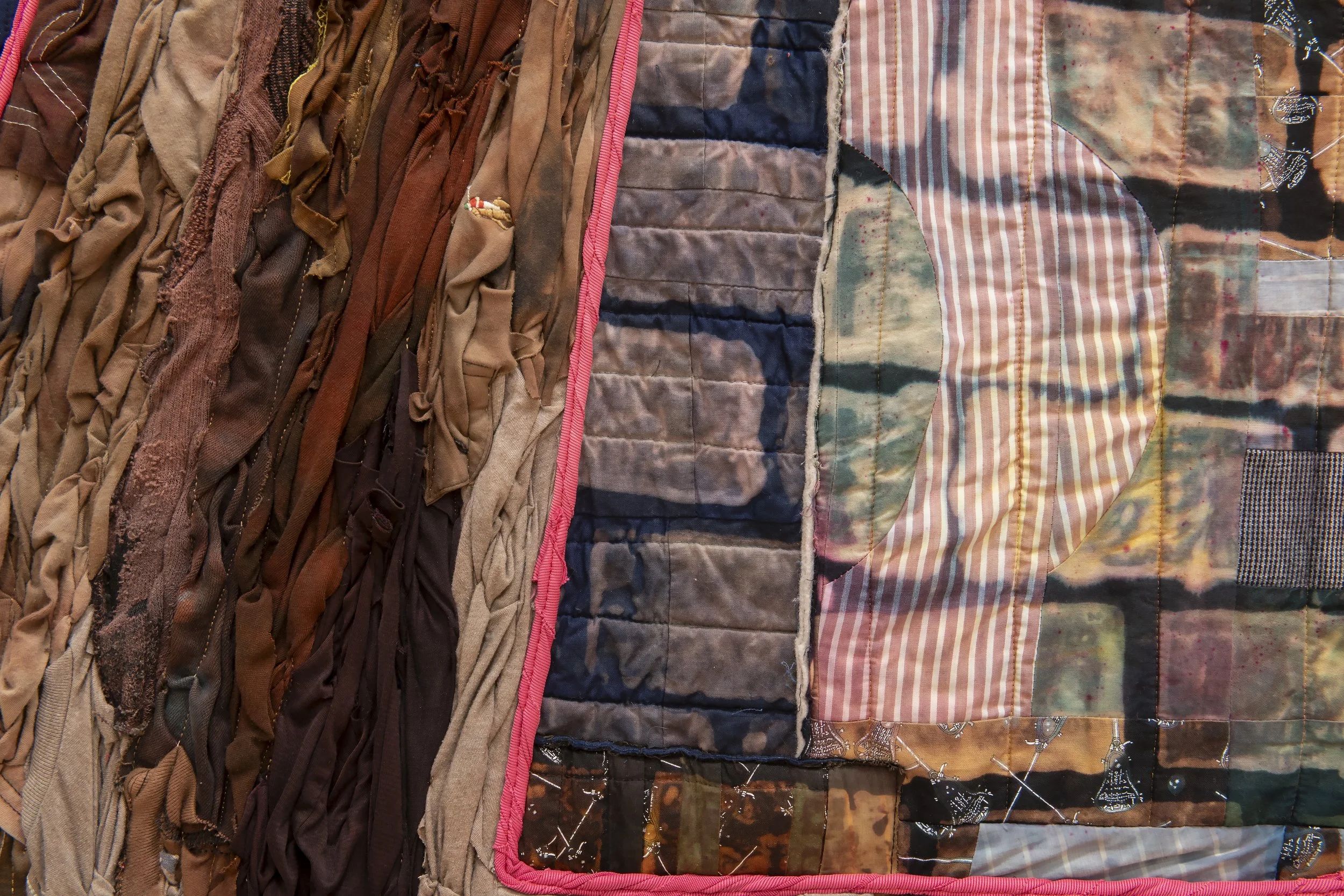 "My Big Ass A" (detail)
t-shirts, shorts, tank tops, jeans found on street and dyed brown; pink pants and grey blanket 
found on trash day; background quilts made in 2020 by artist dyed and bleached. 74” x 90”. Photo Credit: John Carlano