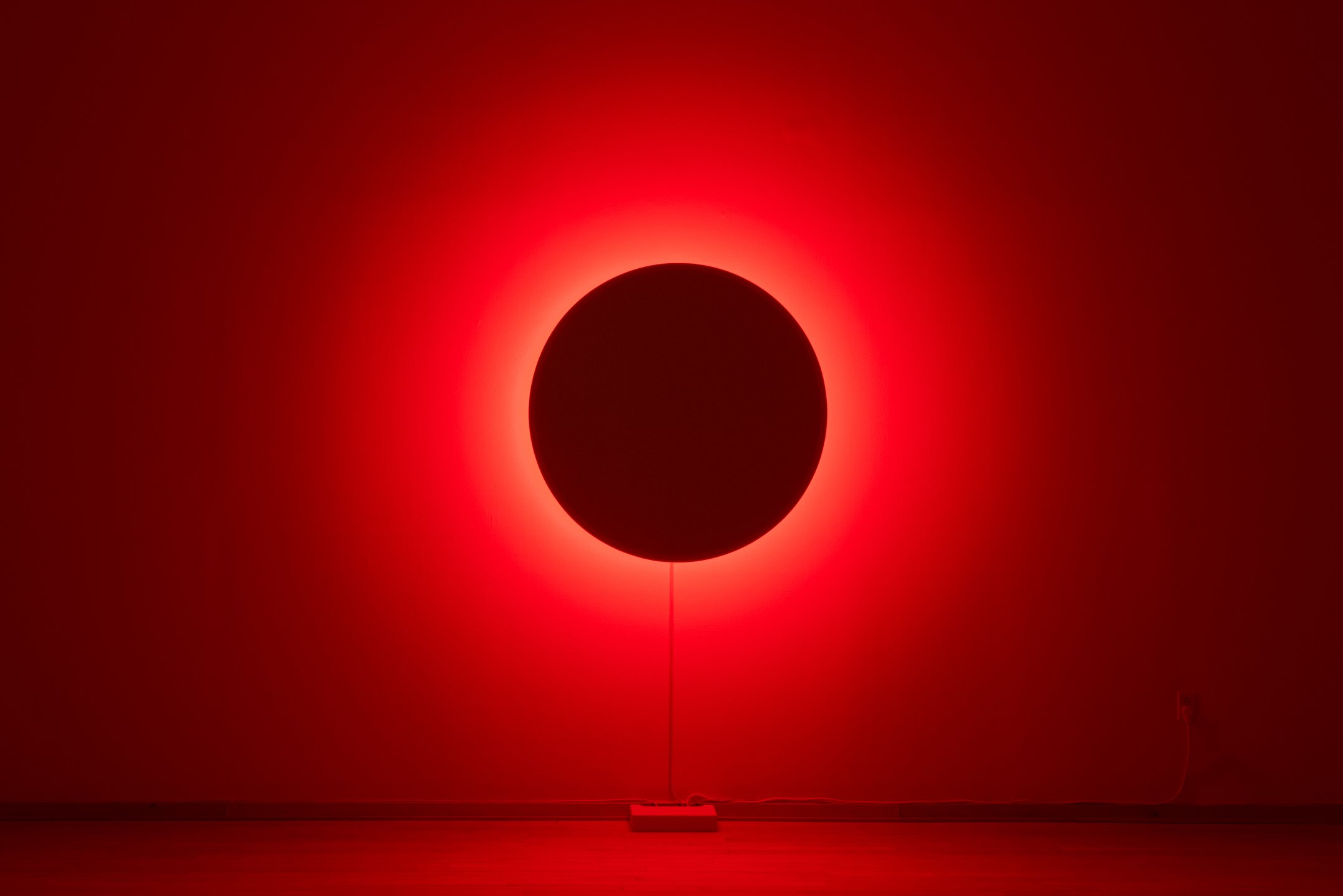"In Totality" (still), 2025, Time-based installation view showing “Optic Disc (Red)," Retroreflective glass microspheres, acrylic paint, foam, steel, LED light, computer controller. 46” by 46” by 14” Photo credit: Neighboring States