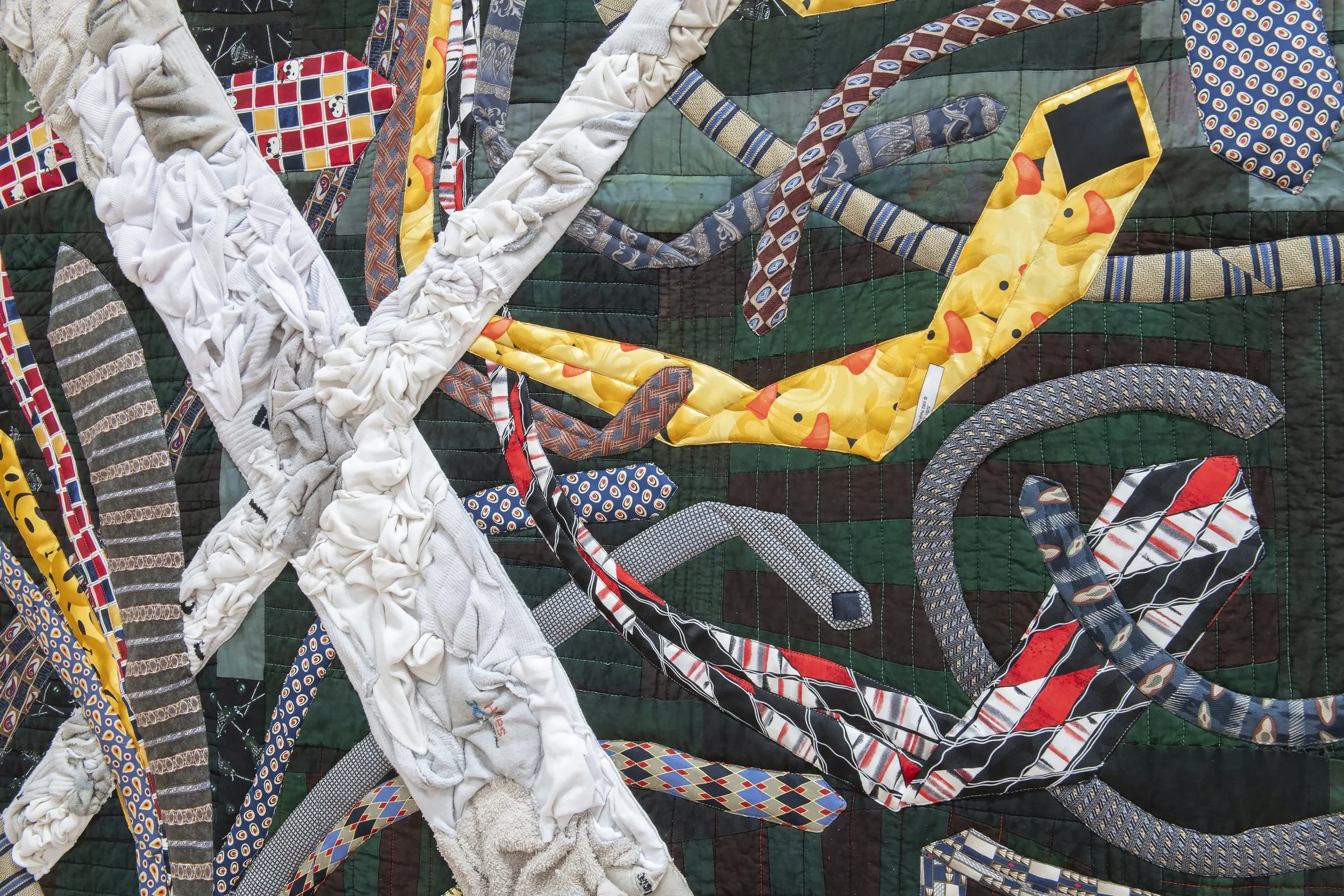 "X’d Out and Tied Up" (detail)
gifted, thrifted, found, and donated ties; white(ish) textiles collected from streets, gutters, and 
trash piles around campus; background quilt made in 2020 by artist and overdyed. 65” x 65”. Photo Credit: John Carlano