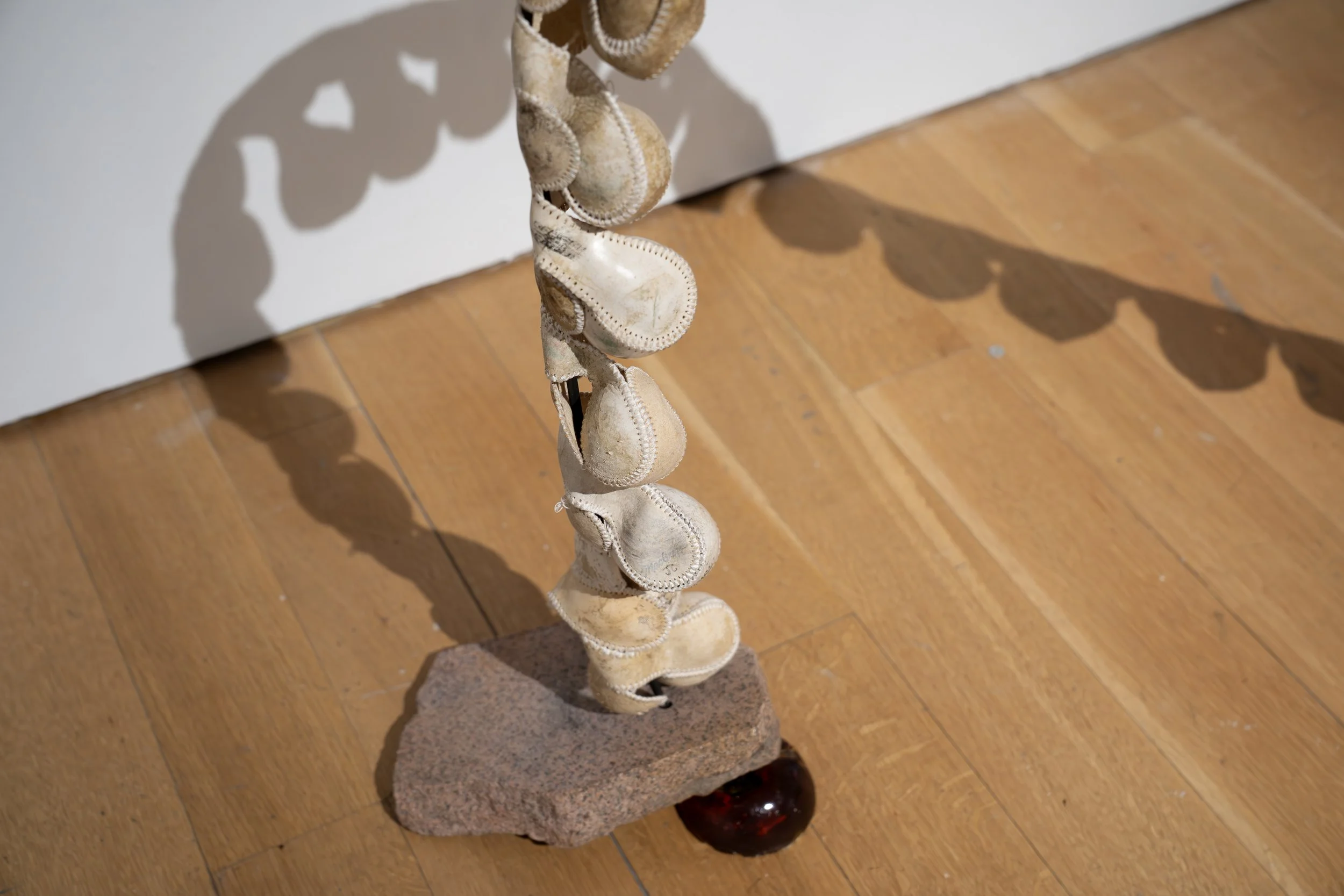 Mary Champagne, 
Spine, 
2026, 
Leather, silk, granite, steel, ball bearings, pine  
rosin, Darth Vader house key. 
42" x 10" x 36" 
