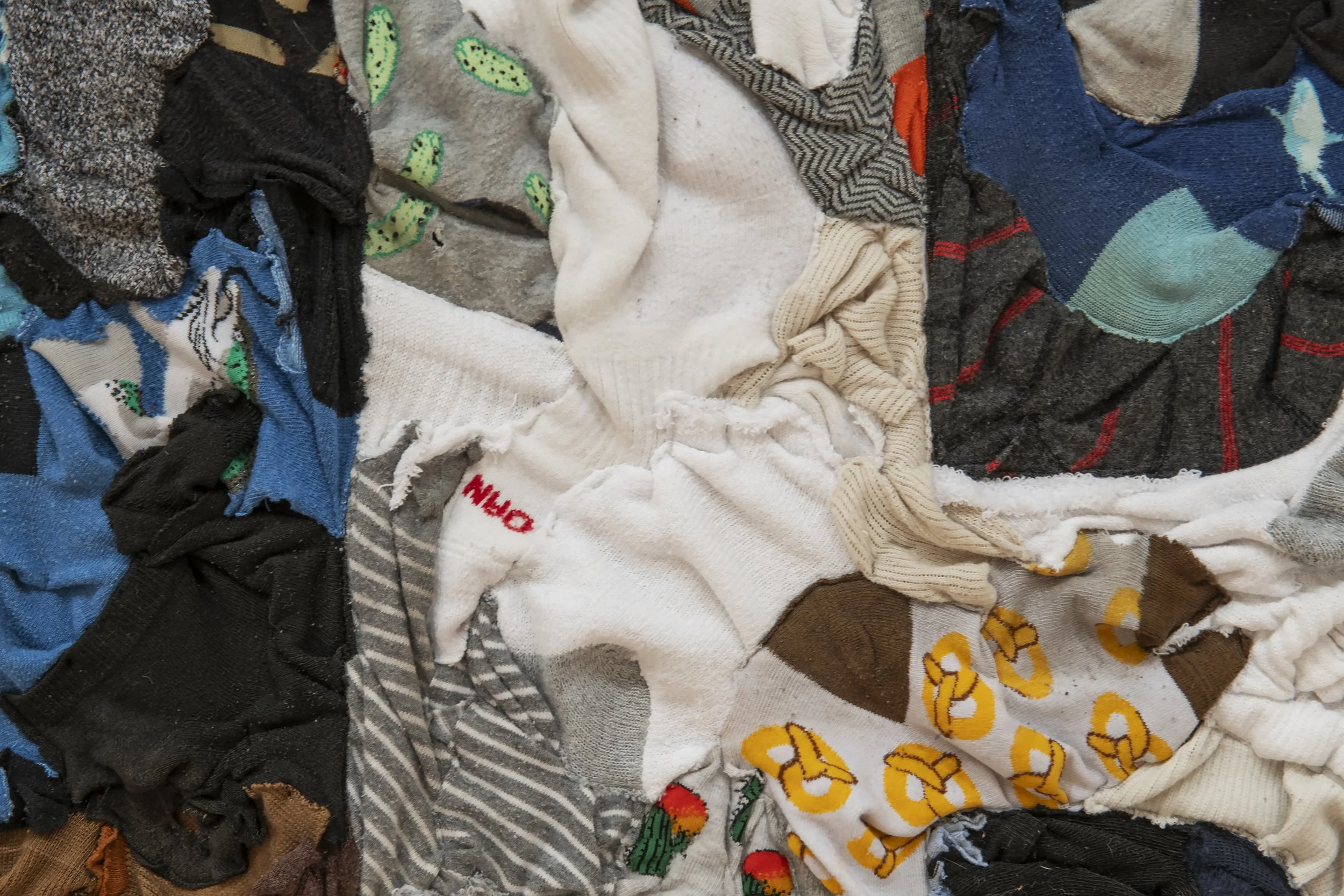 "Diggin’ My Heel into the F Word" (detail)
artists’ worn out/busted out/forgotten/lost crusty socks collected between 2015-2025; backed 
with vintage wool blanket. 37” x 54”. Photo Credit: John Carlano