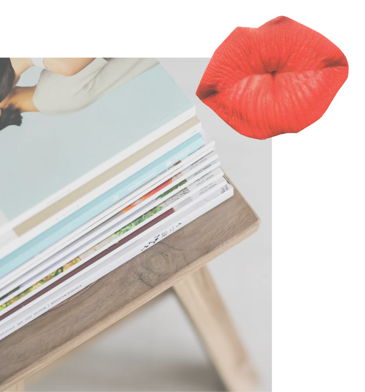 A stack of magazines or books on a wooden table, with a woman in a beige coat visible in the background, and a large red lipstick kiss mark decoration near the top right of the image.