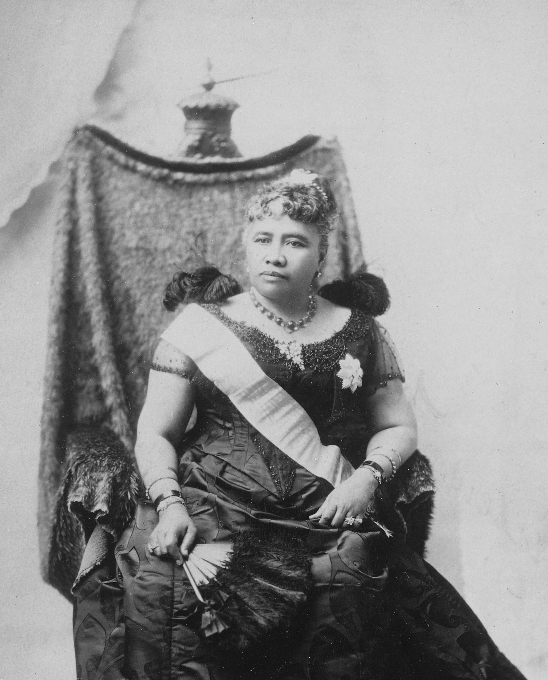 Liliuokalani_sitting_on_chair_draped_with_feather_cloak.jpg