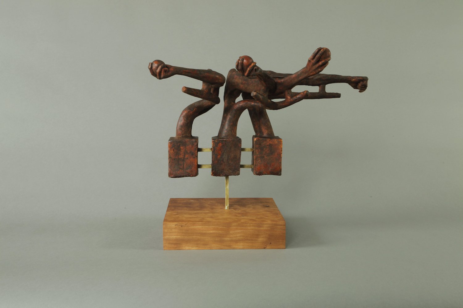 This sculpture captures the dynamic motion of a baseball pitcher’s arm mid-throw, crafted from iron, concrete, brass, and cherry wood. The elongated iron arm stretches forward, with fingers curled as if gripping an invisible baseball. The arm’s muscu