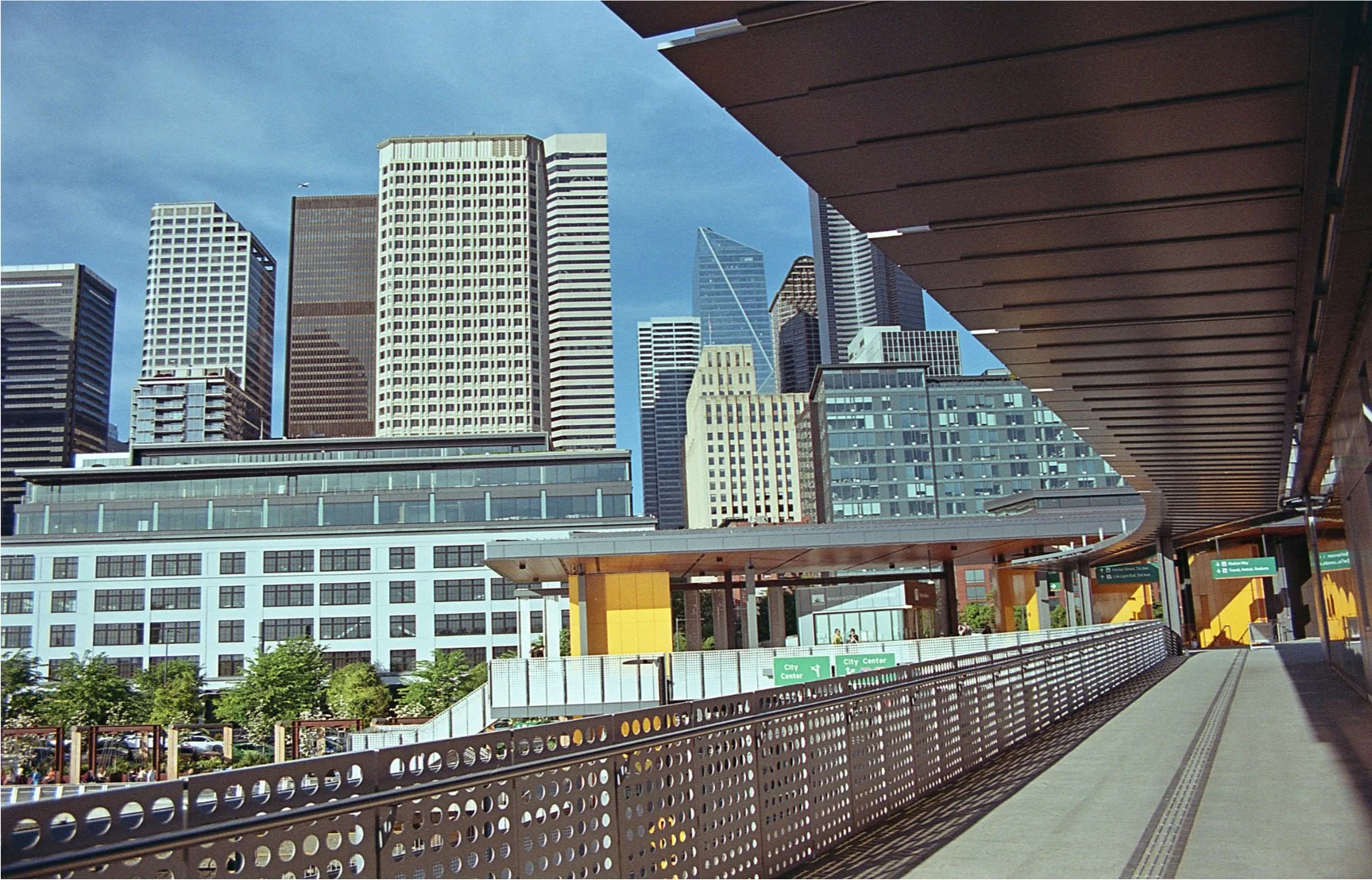 Picture taken from DOwntown Seattle ferry dock, looking towards Downtown. The ceiling of the outdoor terminal area and the raiing provide framing for the skyscrapers beyond. Taken on Fujifilm 200 using my Nikon F4004, during the 'Ferries on FIlm' eve