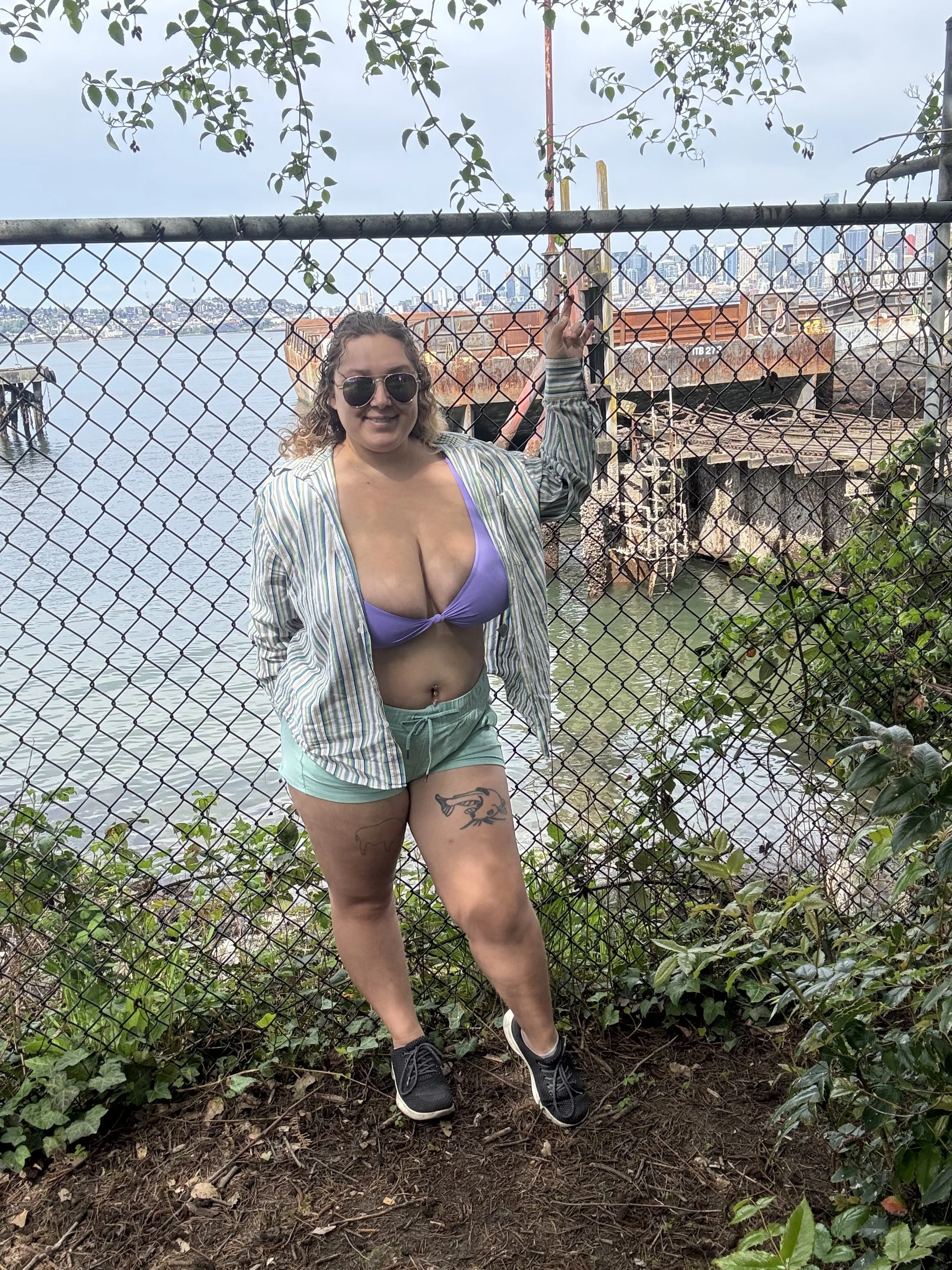 Arianna in front of a chain link fence, with Puget Sound in the background