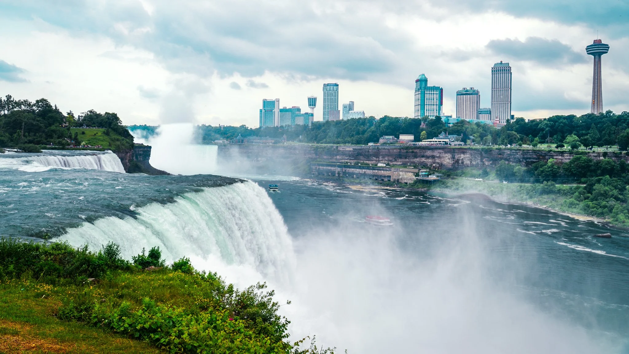View of Niagara Falls with city skyline in the background, including the Skylon Tower and Casino.