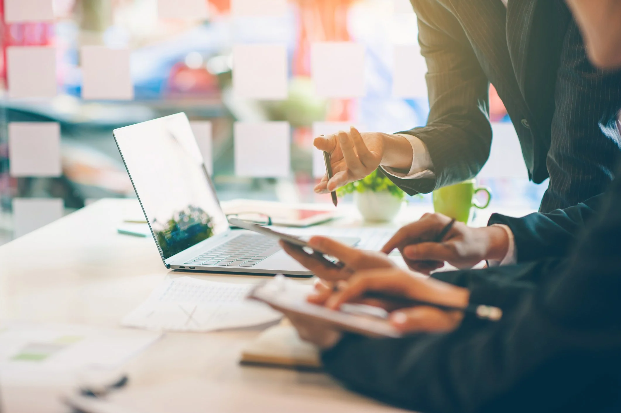 Team collaborating around a desk with documents, a laptop, and a tablet, brainstorming ideas in a modern business consulting environment.