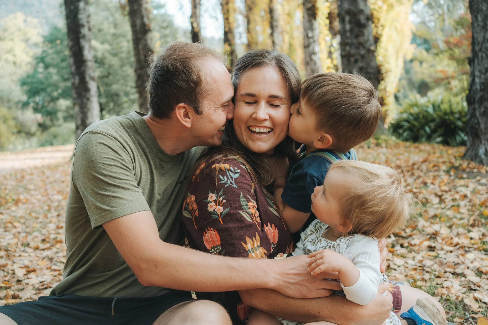 family huggins eachother in the autumn leaves at bright, victoria, Australia
