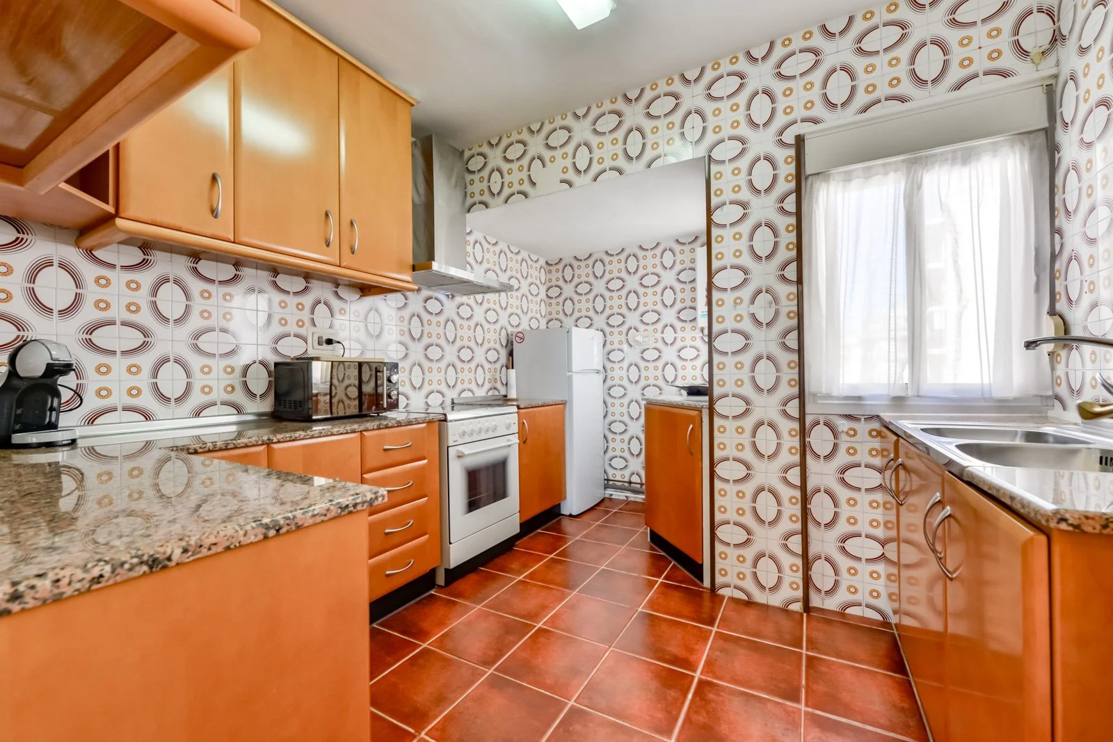 Keuken van het vakantieappartement in Calpe met retro‑tegels, houten kasten, oven, koelkast en veel natuurlijk licht.