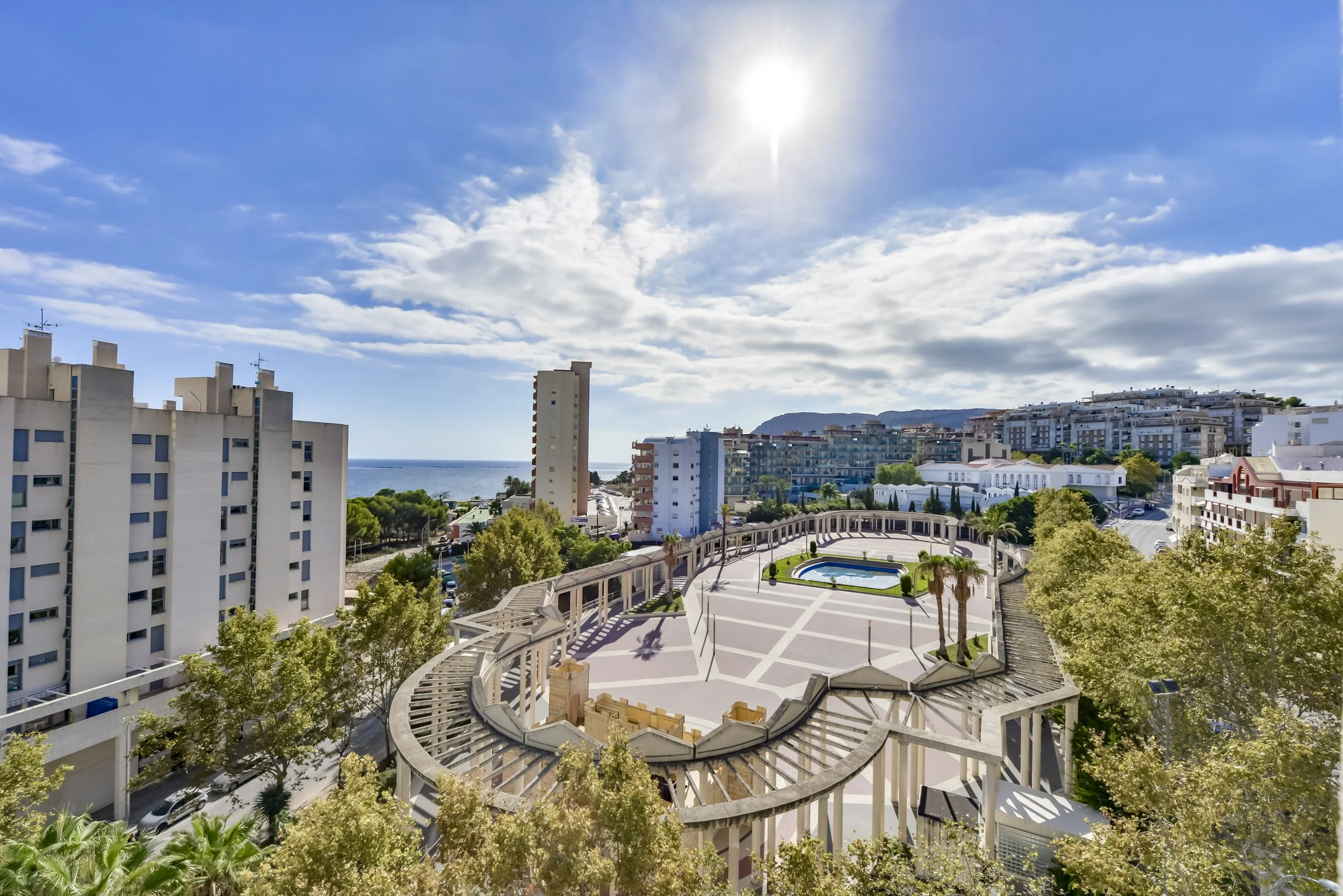 Uitzicht op Calpe met plaza, fontein, palmbomen en de Middellandse Zee op de achtergrond — sfeerbeeld van de omgeving van ons vakantieappartement.
