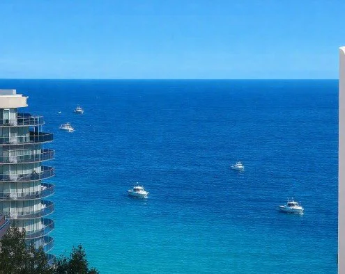 Zeezicht vanuit vakantieappartement in Calpe, met moderne residentie links en enkele boten op de helderblauwe Middellandse Zee, aan Arenal Bol strand in calpe — ideale ligging bij Belgische eigenaars op toplocatie.