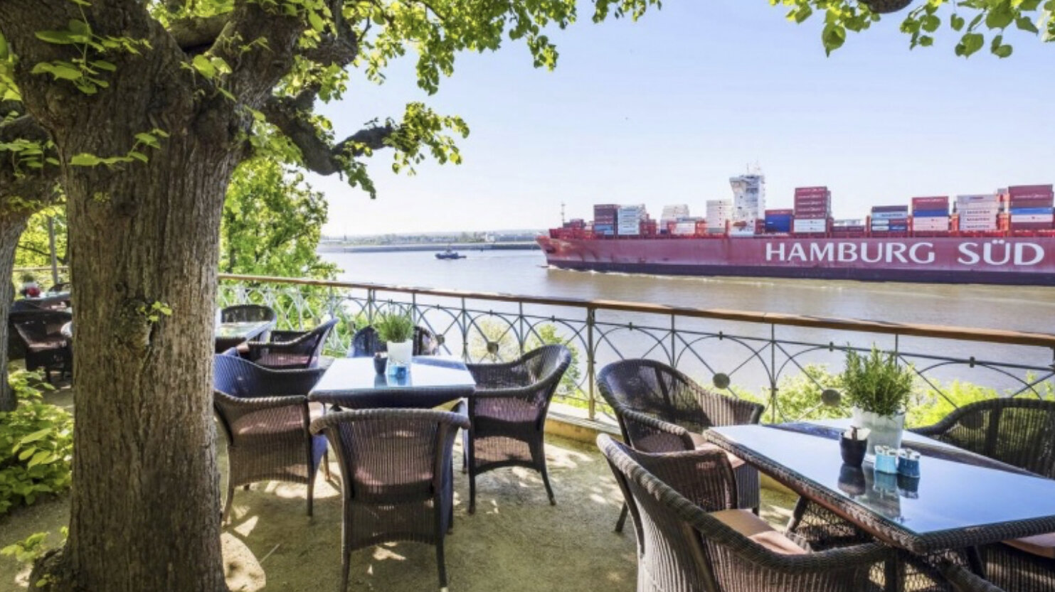A ship in Hamburg sails past a café.