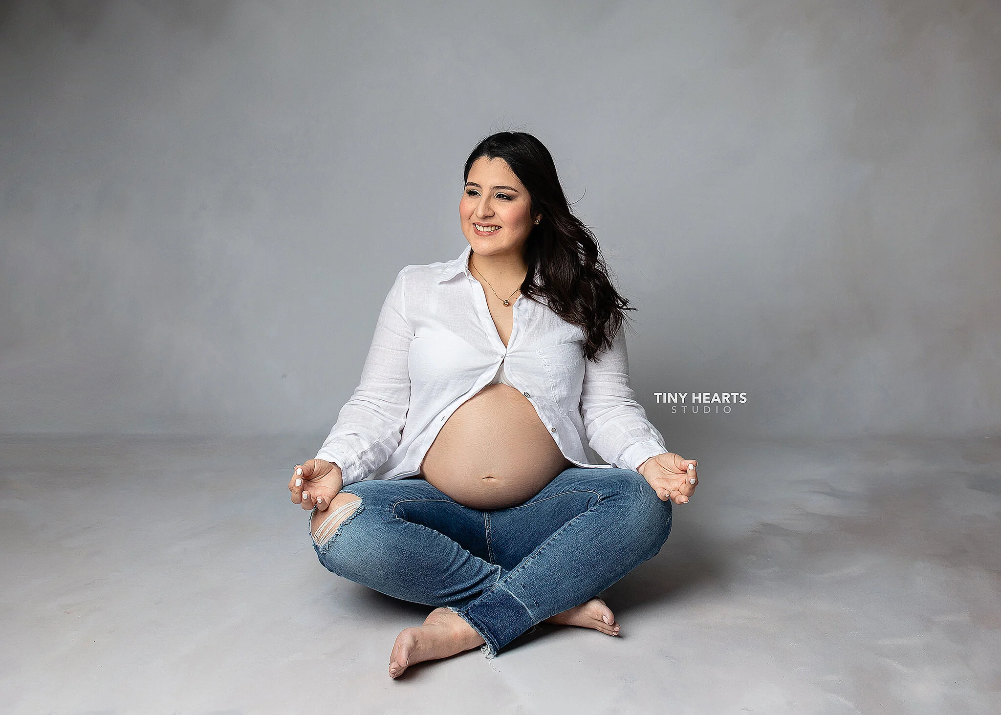 pregnancy pictures, pregnant woman in casual attire seated in sukhasana pose