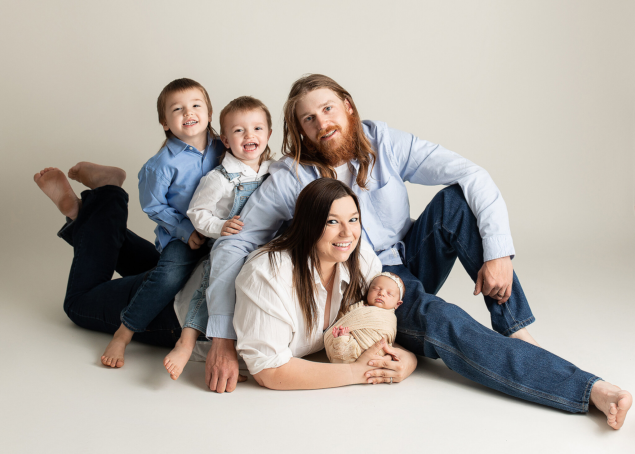 newborn and family photoshoot, parents lying on floor with kiddos on back holding baby girl