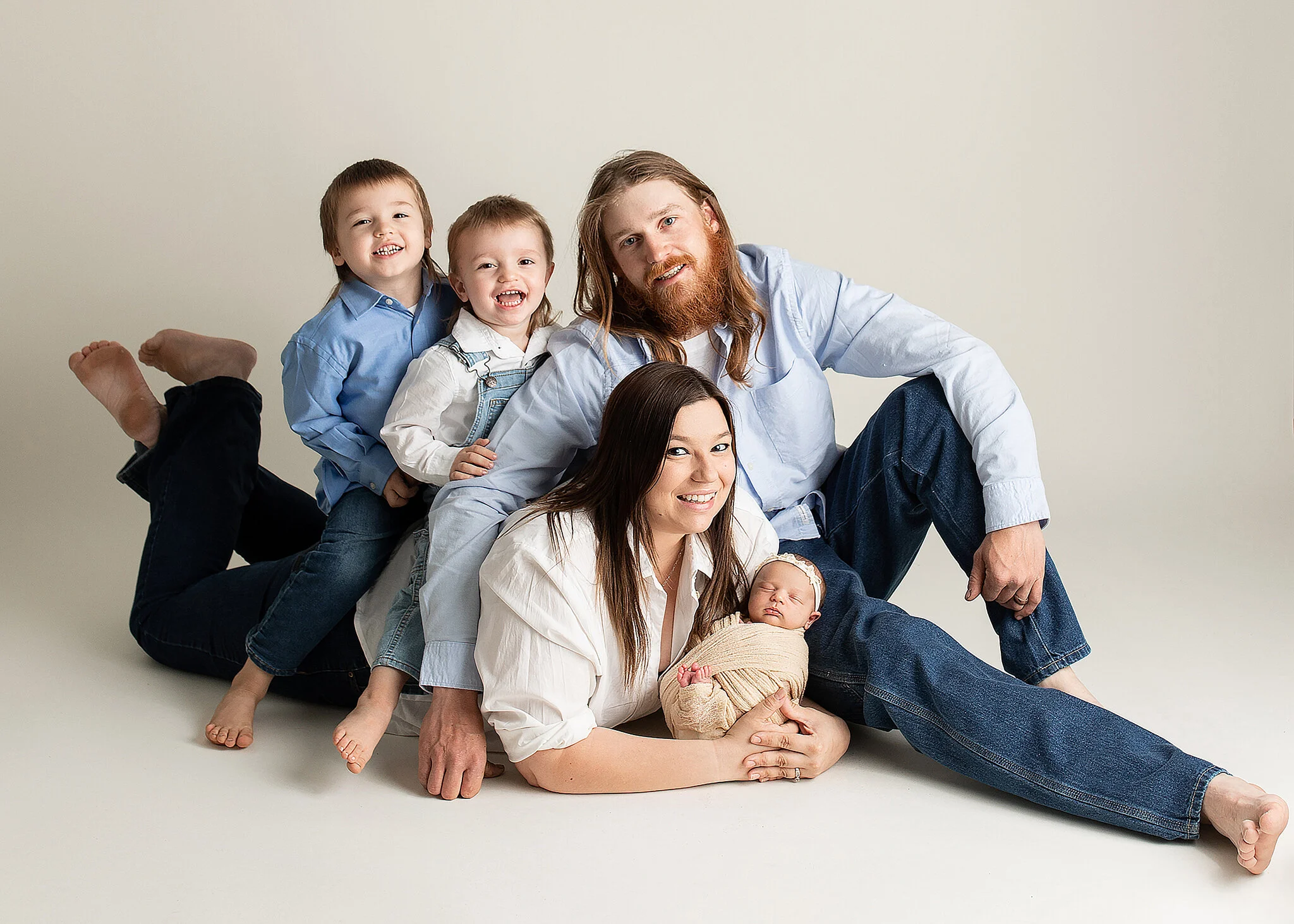 newborn and family photoshoot, parents lying on floor with kiddos on back holding baby girl