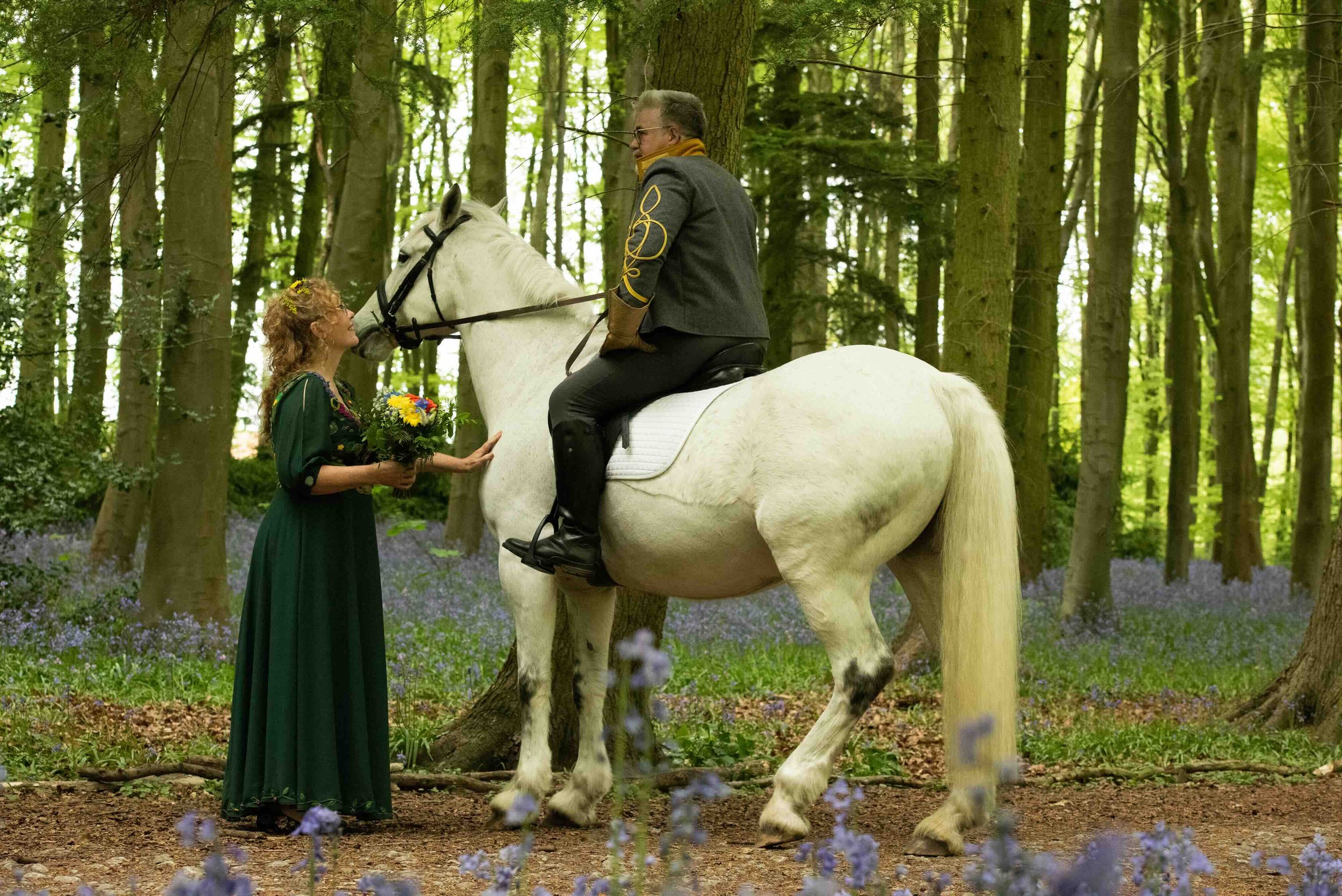 Groom arrives on horseback in the bluebell woods of Erlestoke for his handfasting wedding ceremony 