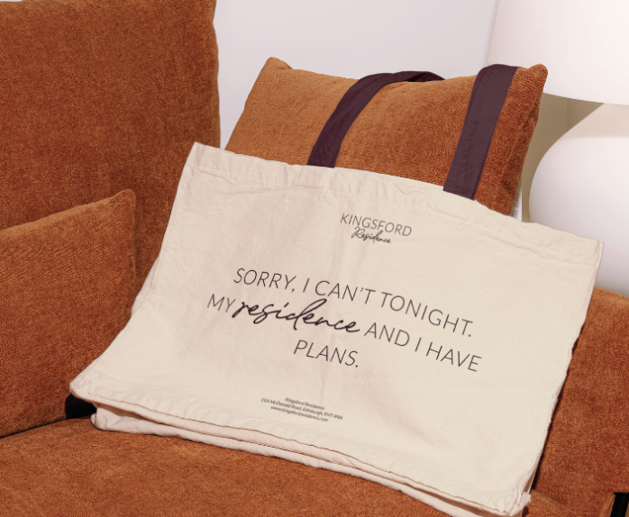 Decorative pillow with a quote on a burnt orange couch, with a white lamp in the background.