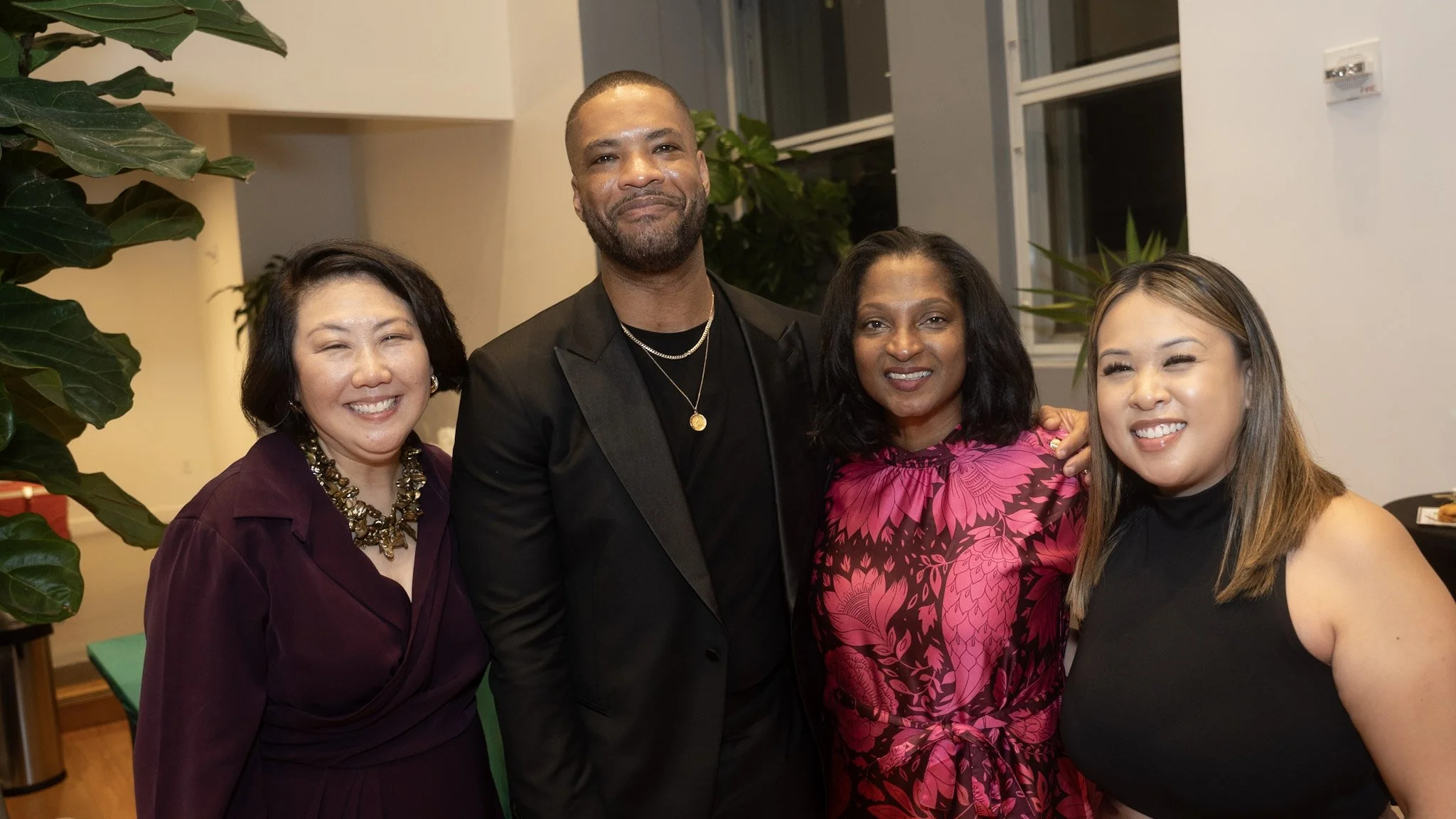 Four smiling people standing next to each other