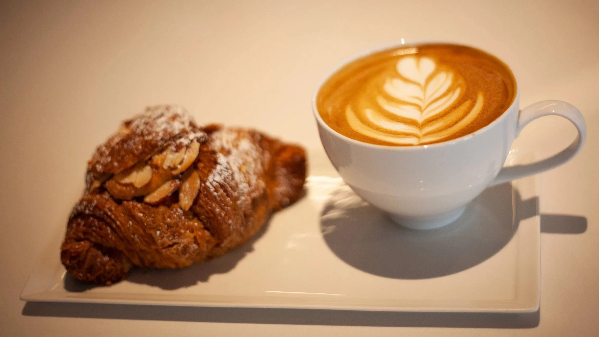 Latte with leaf art and almond pastry at Abanico Coffee Roasters in San Francisco.