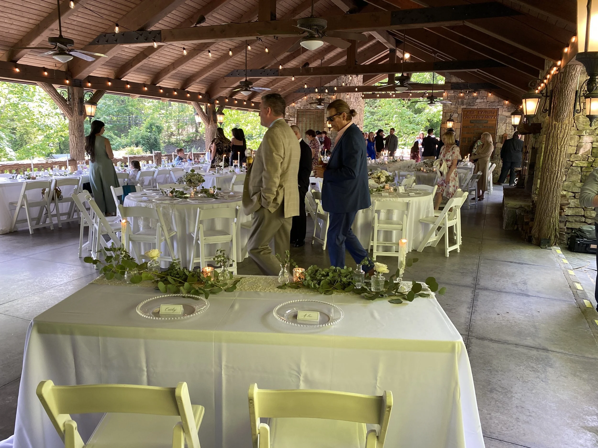 Guests gathering for Carley and Alec’s reception under the timber roof at The Pavilion at Lake Rabun.