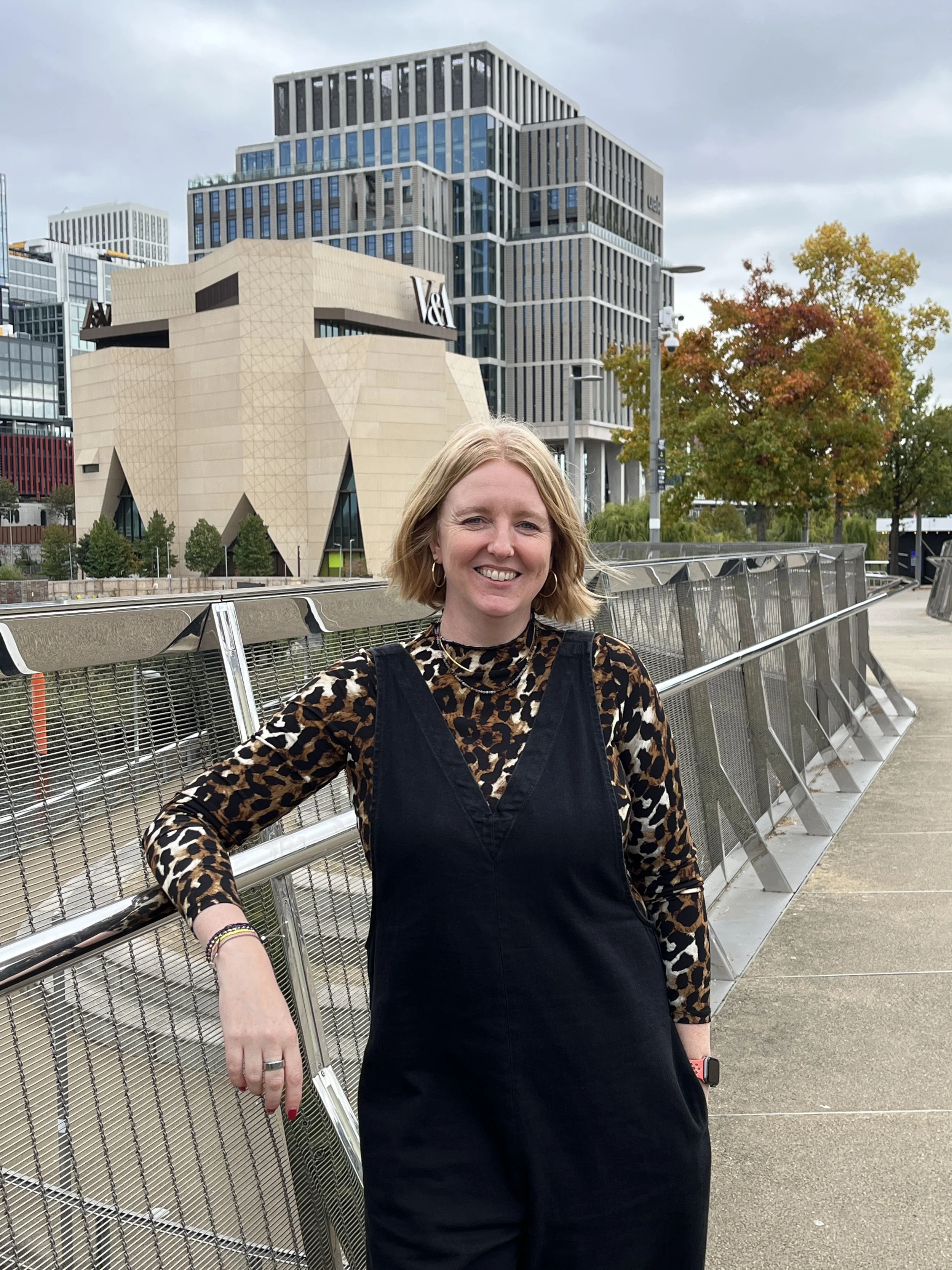 Leaning leaning against a metal barrier smiling to camera