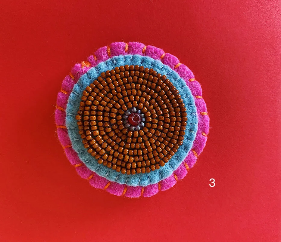Photo of option 3: a colorful hand-sewn & beaded felt brooch of various skin tones that looks like tatas.