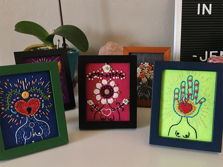 Group photo of three hand embroidered and beaded goddesses in frames on a shelf.