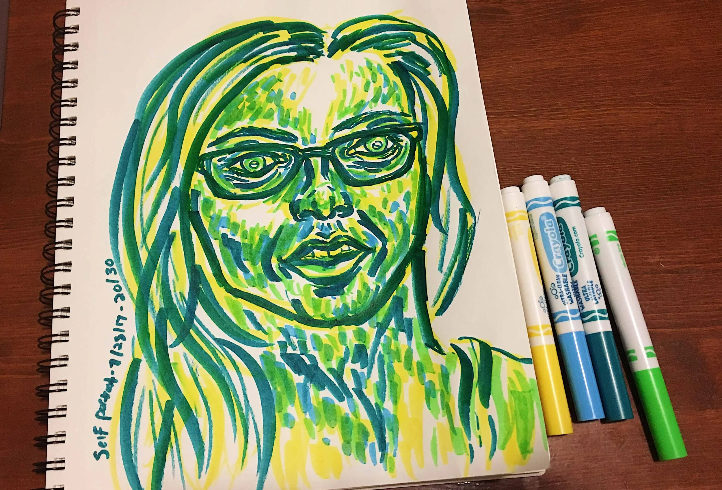 Day 20: photo of a marker self-portrait wearing glasses surrounded by art supplies on a table.