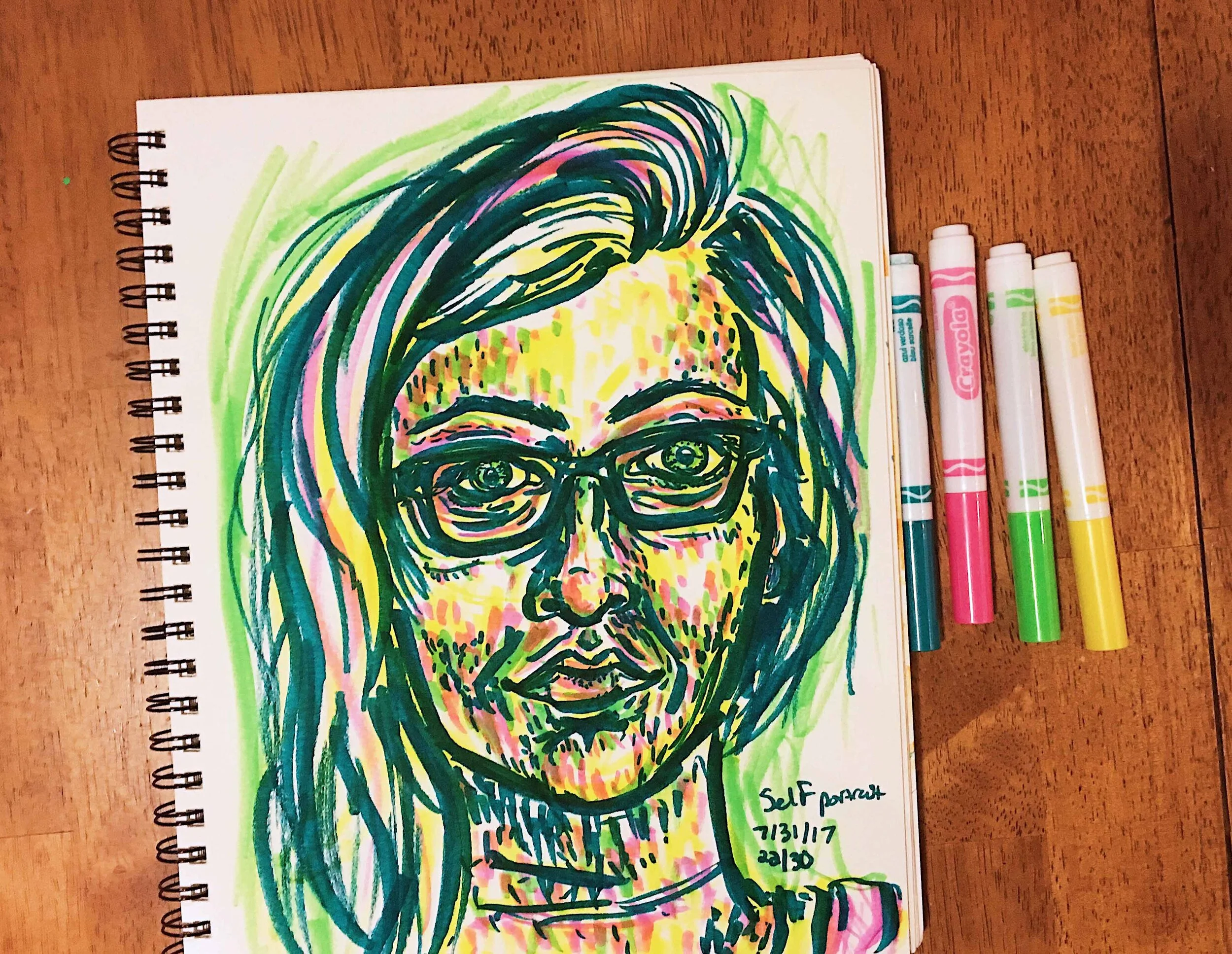 Day 22: photo of a marker self-portrait wearing glasses surrounded by art supplies on a table.