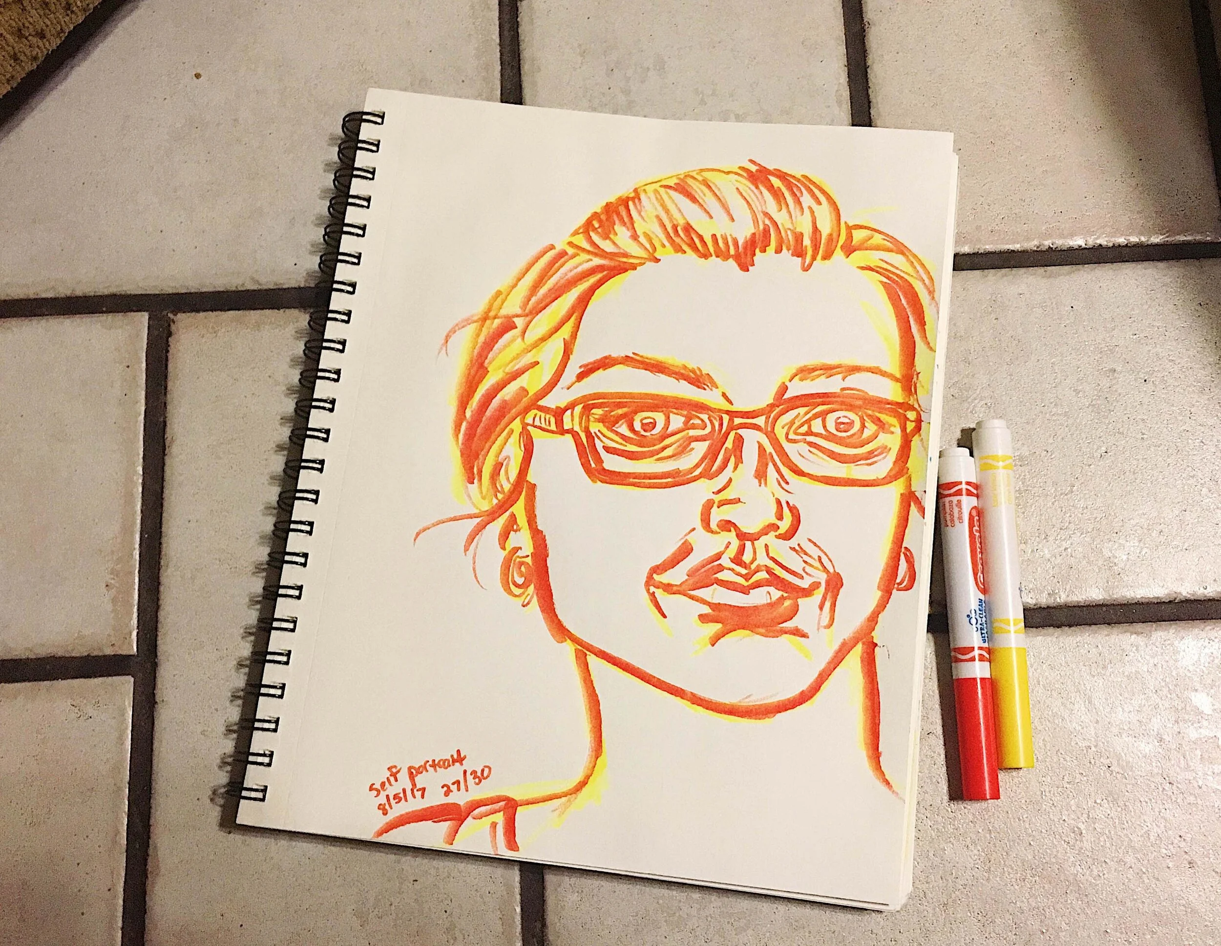Day 27: photo of a marker self-portrait wearing glasses surrounded by art supplies on a tile floor.