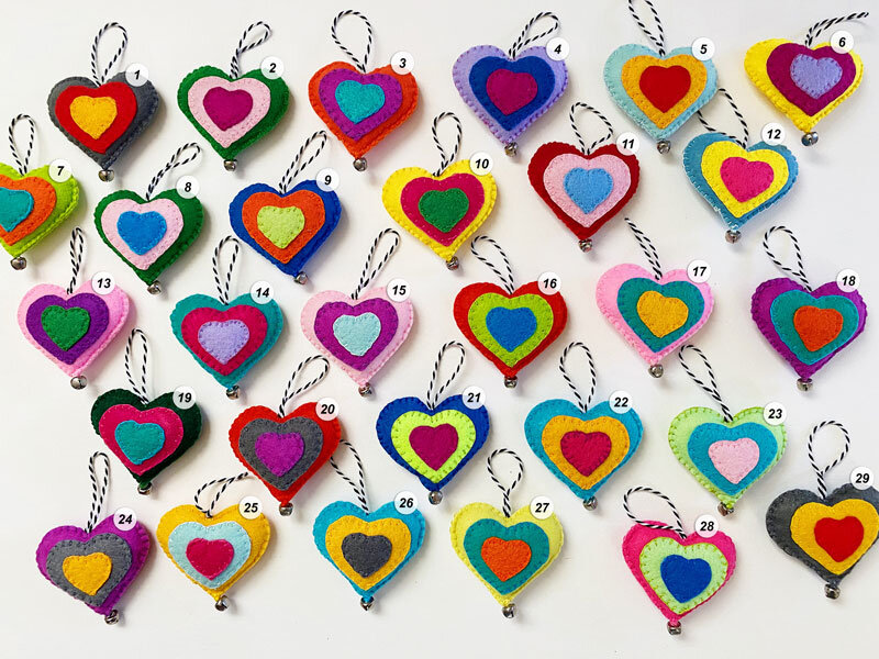 Overview photo of colorful, hand-sewn felt heart ornaments on a white background and their corresponding numbers.