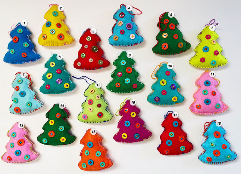 Overview shot of numbered, hand-sewn felt tree ornaments embellished with colorful buttons on a white background.